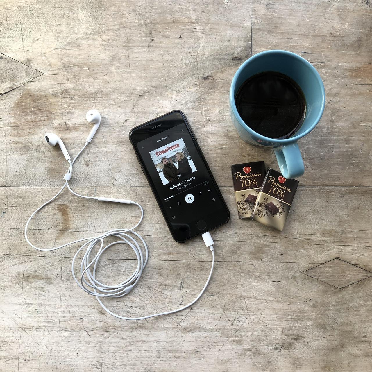 Kahve ve çikolata ile kulaklık takılı telefondan podcast