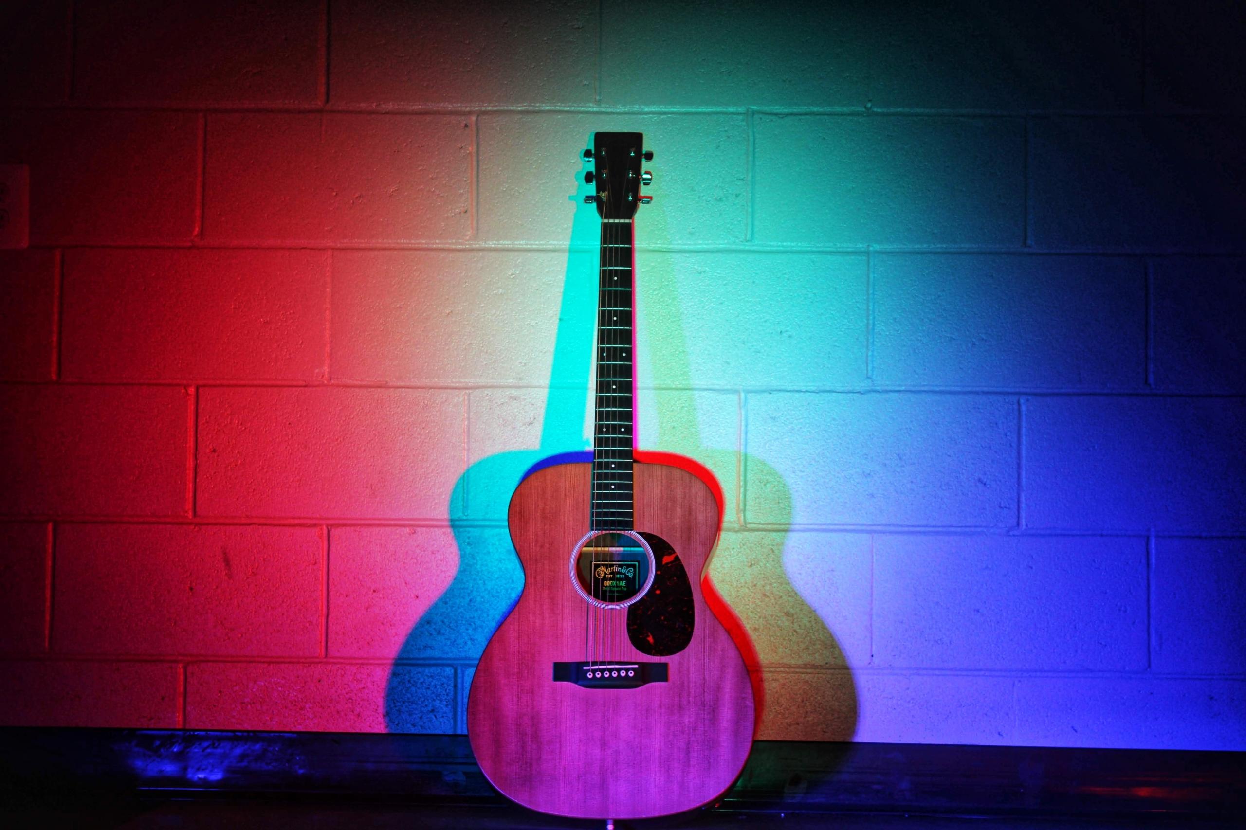 Mavi kırmızı ışıklar altında duran akustik gitar