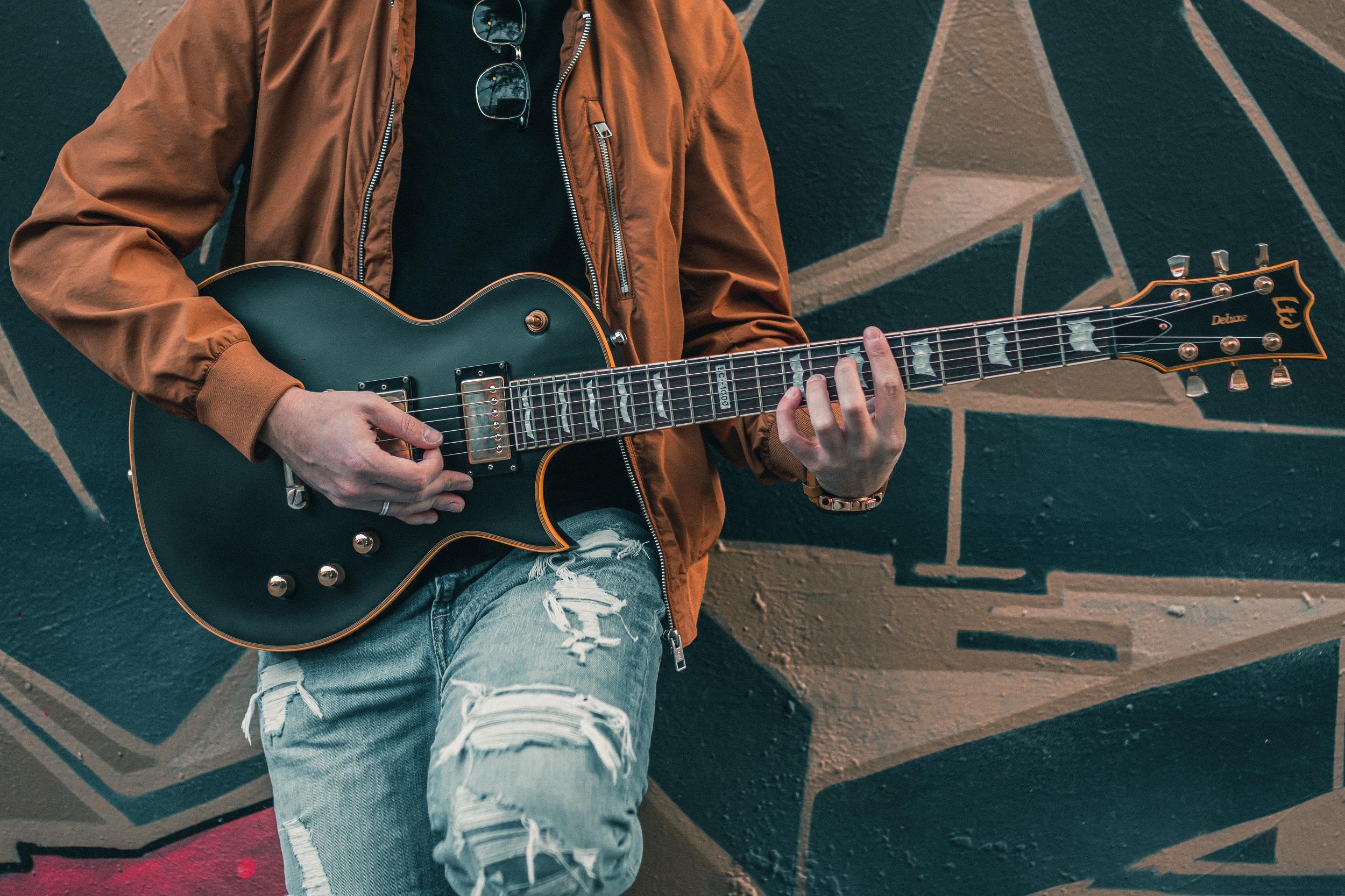Siyah elektro gitar çalan yırtık kotlu adam