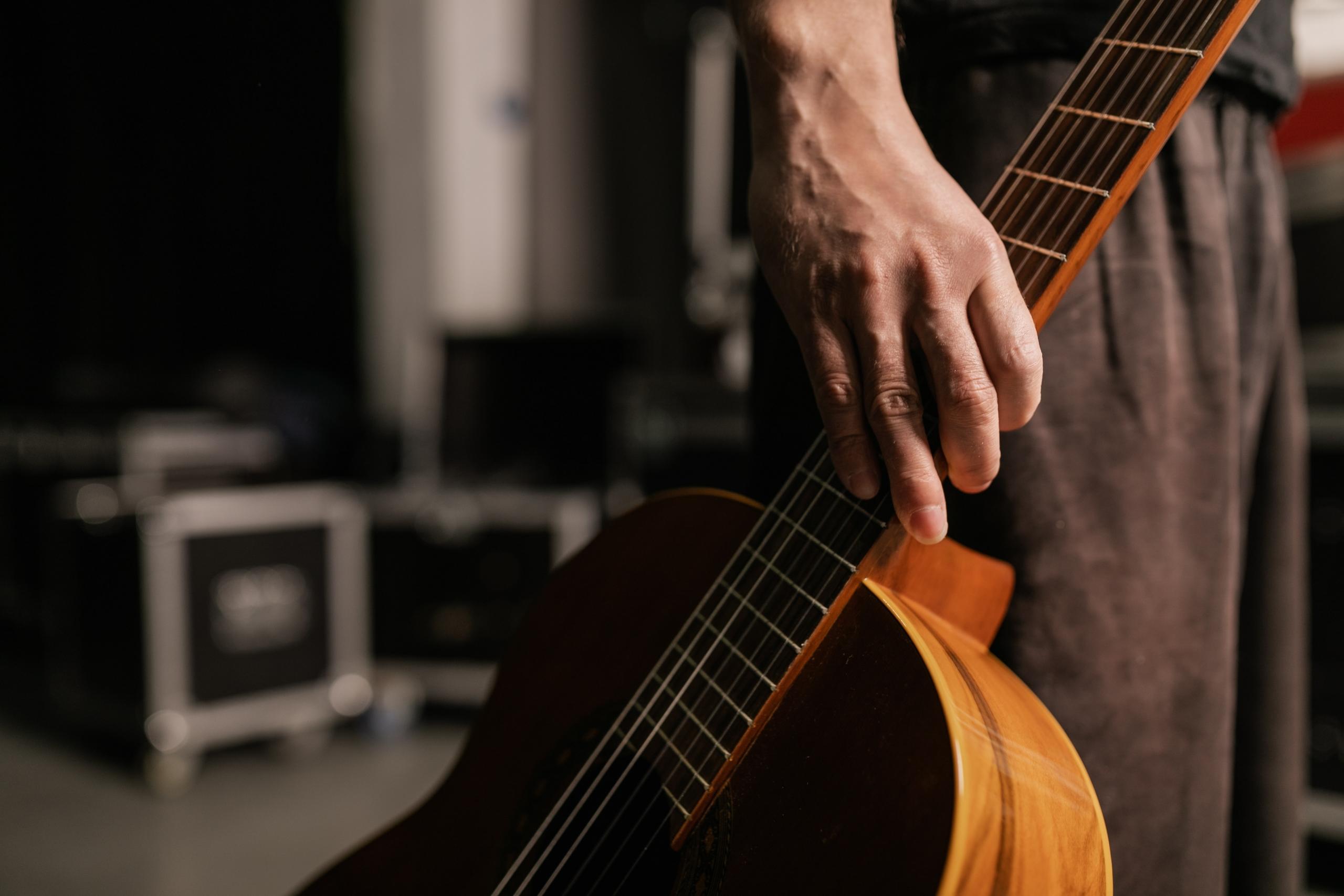 Klasik gitarın sapını tutan erkek eli