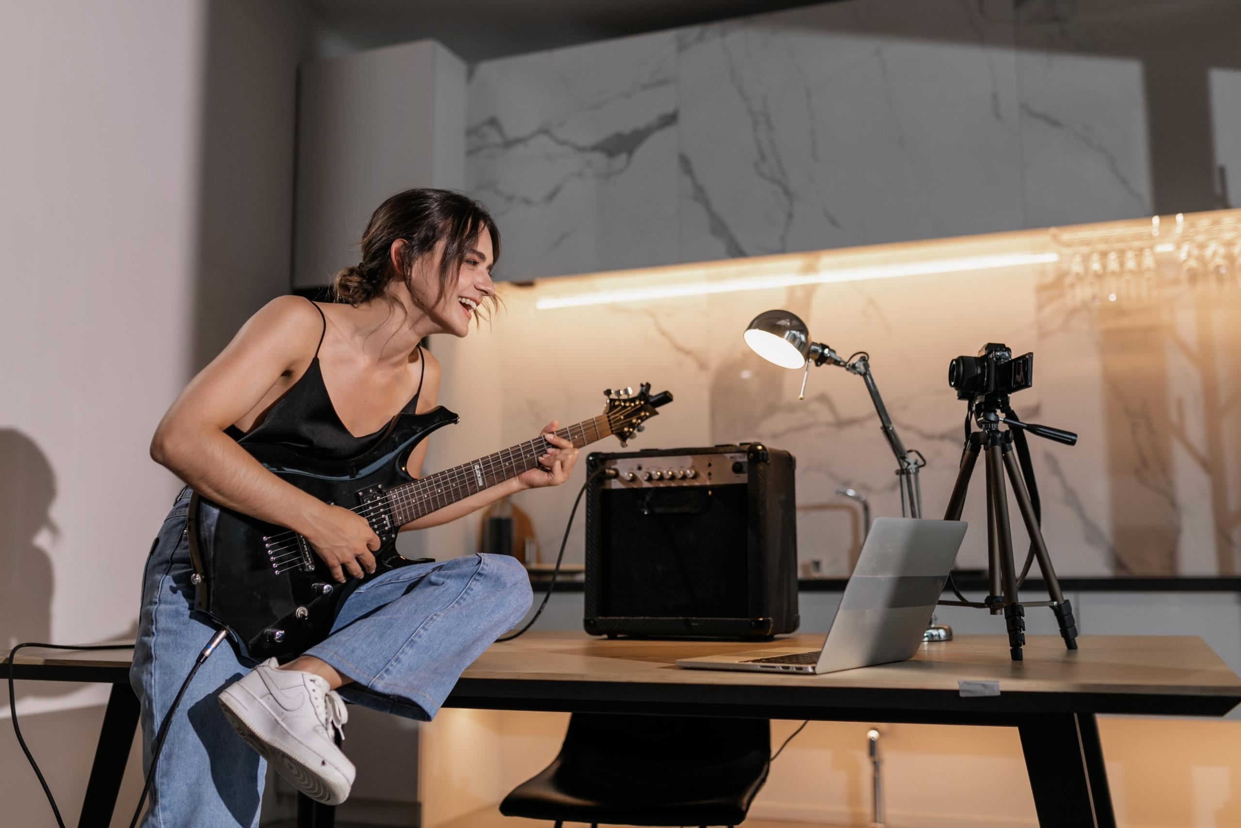 Masada otururken siyah elektro gitar çalan kız
