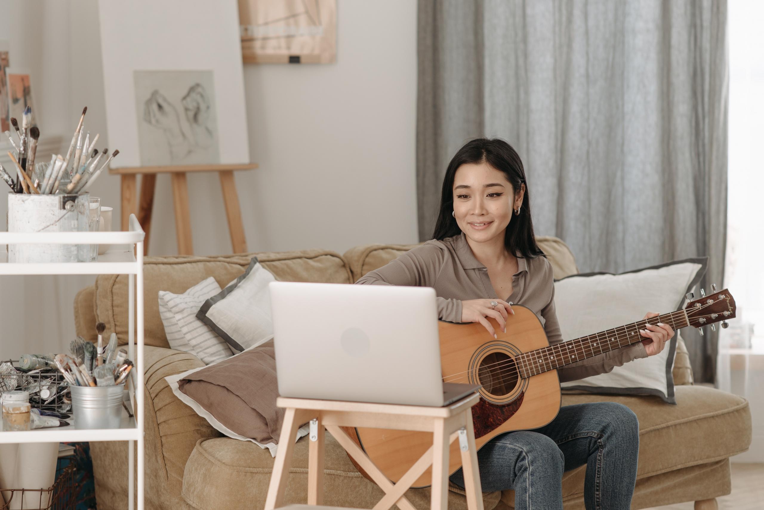 Evde laptopa bakarken klasik gitar çalan kız