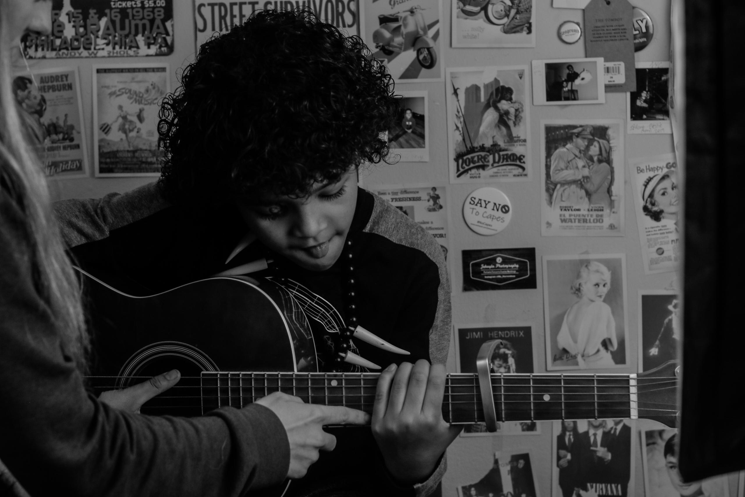 Gitar çalan çocuğun gitarını tutan eller