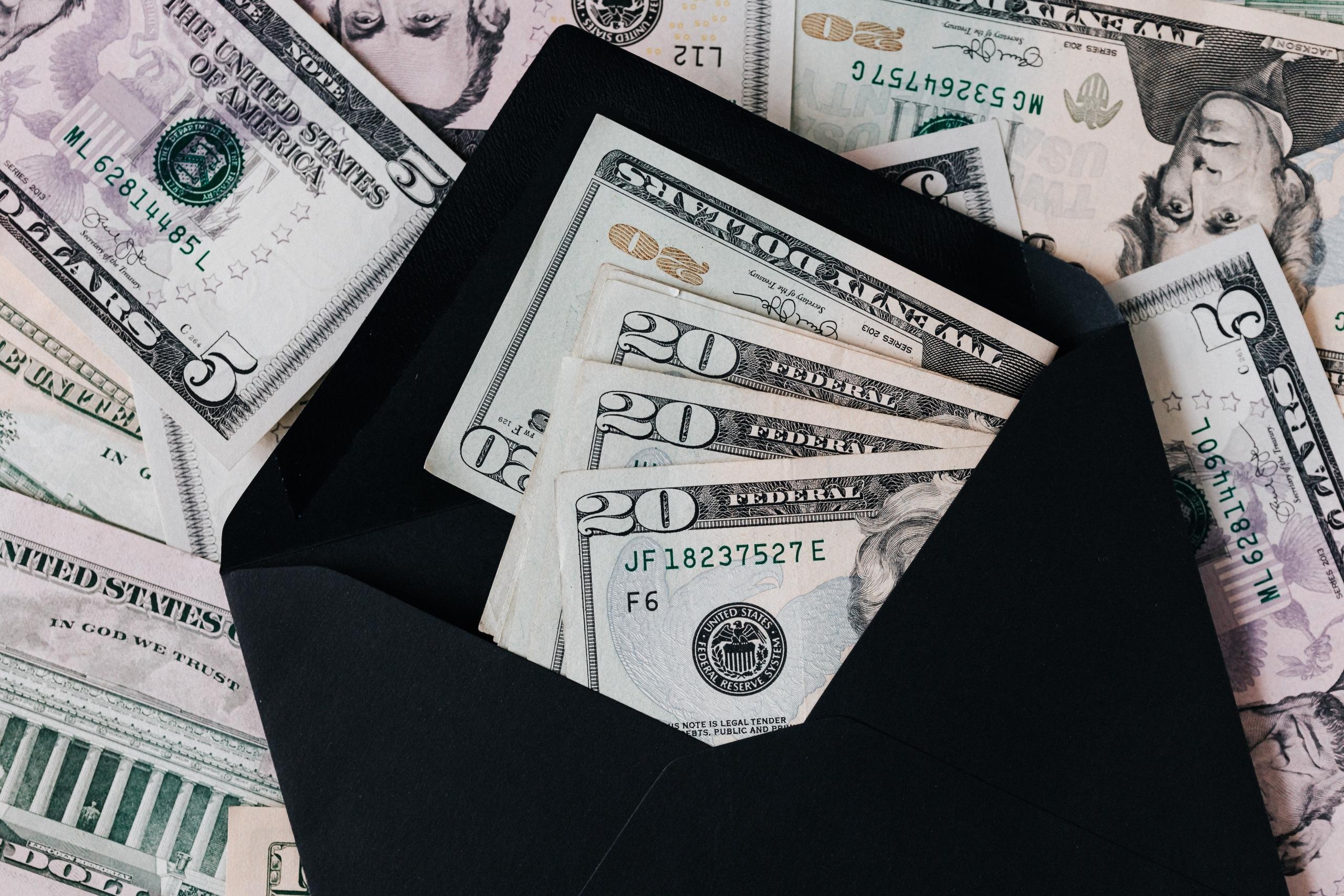Banknotların üstünde siyah zarfın içinde kâğıt paralar