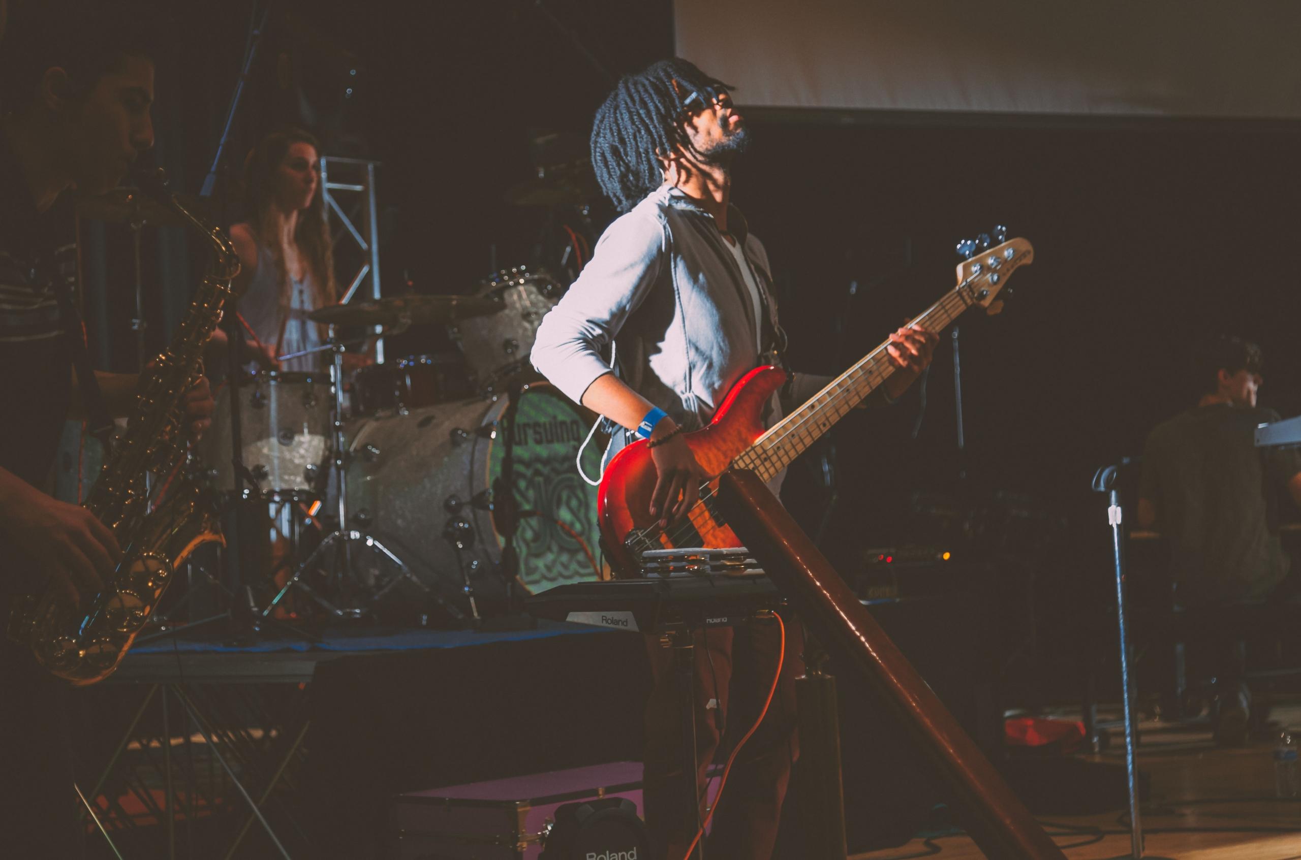 Kırmızı gitar çalan kıvırcık saçlı adam