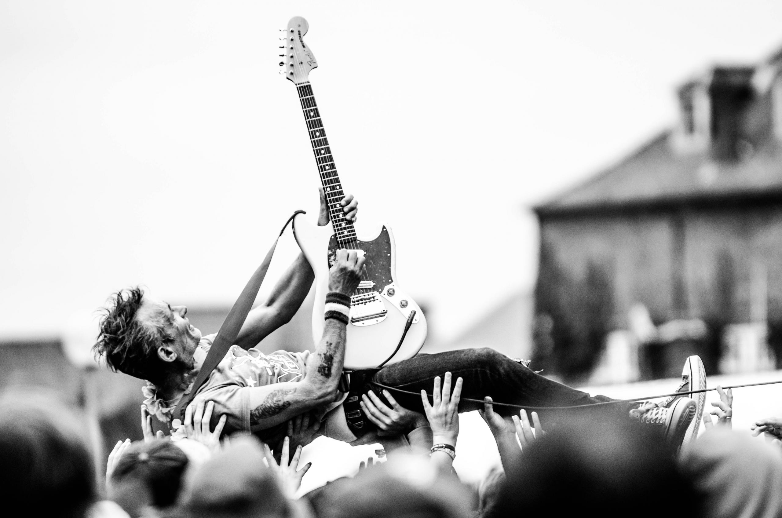 Konserde seyircilerin üstünde gitar çalan adam
