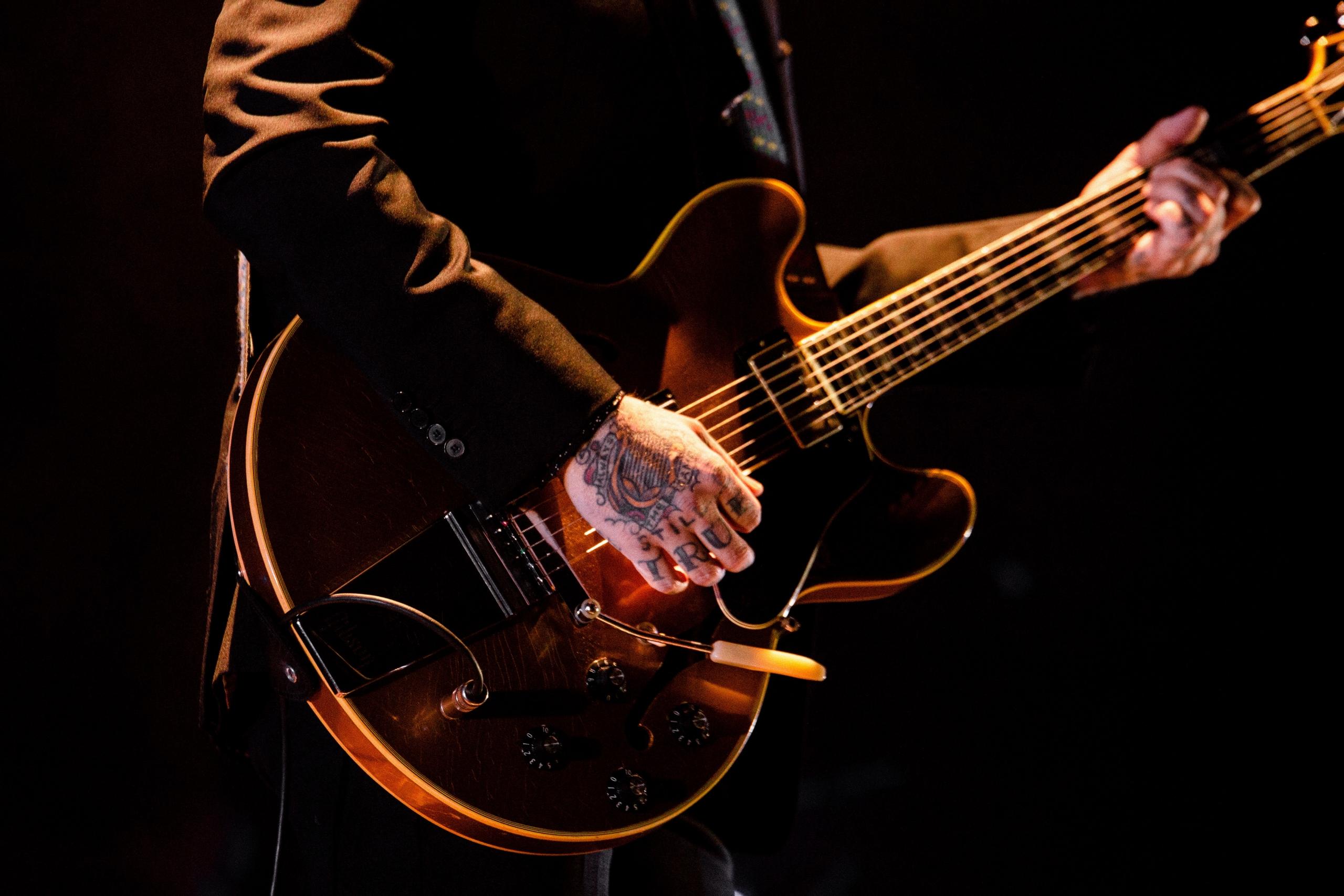 Gitar çalan eli dövmeli adam