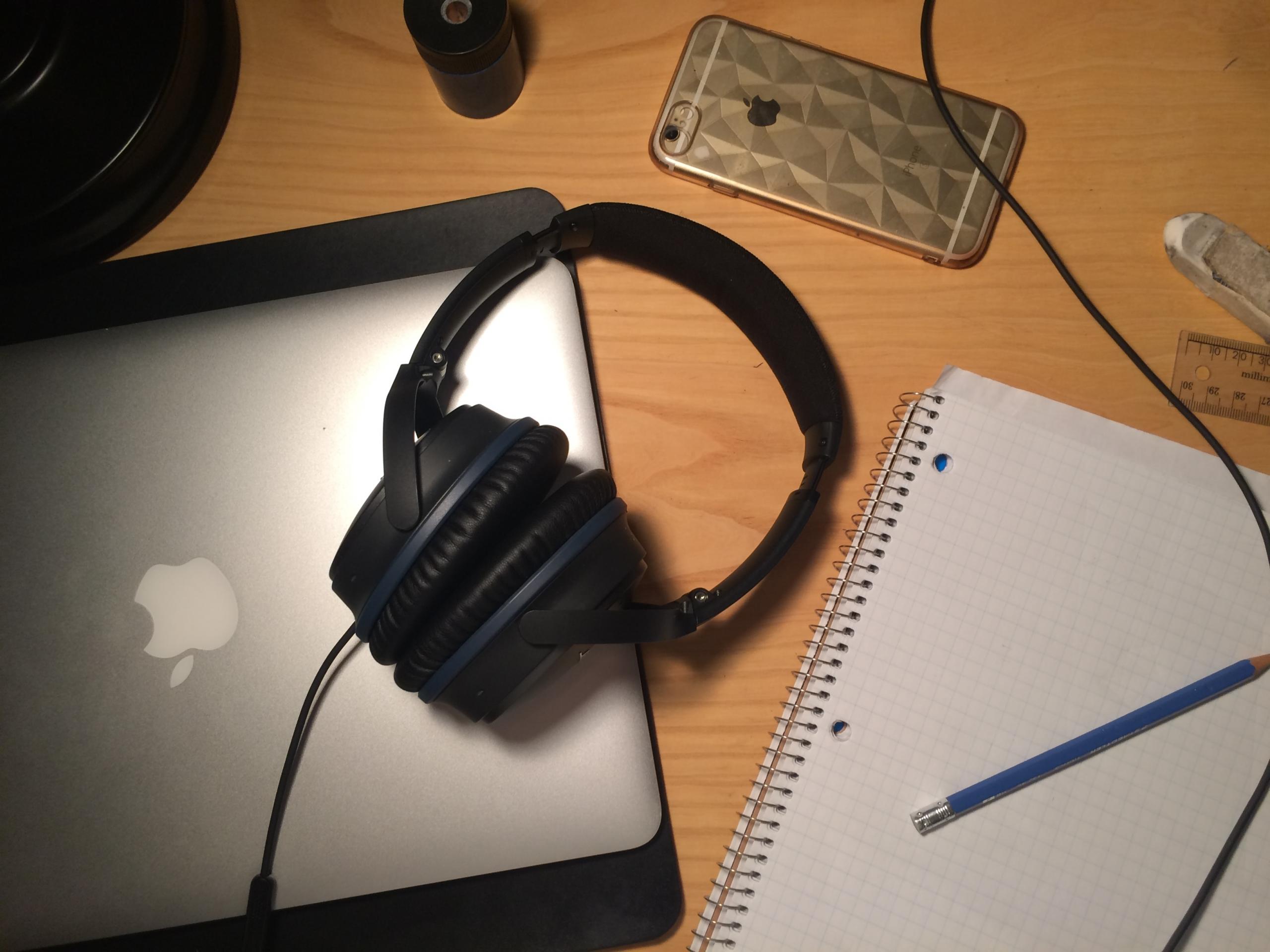 Masanın üstünde laptop kulaklık defter kalem