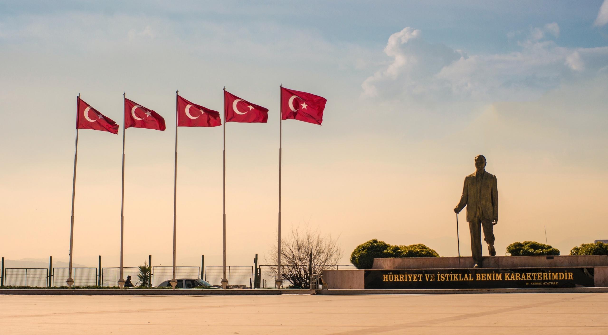 Direklerde dalgalanan bayrakların yanında Atatürk heykeli
