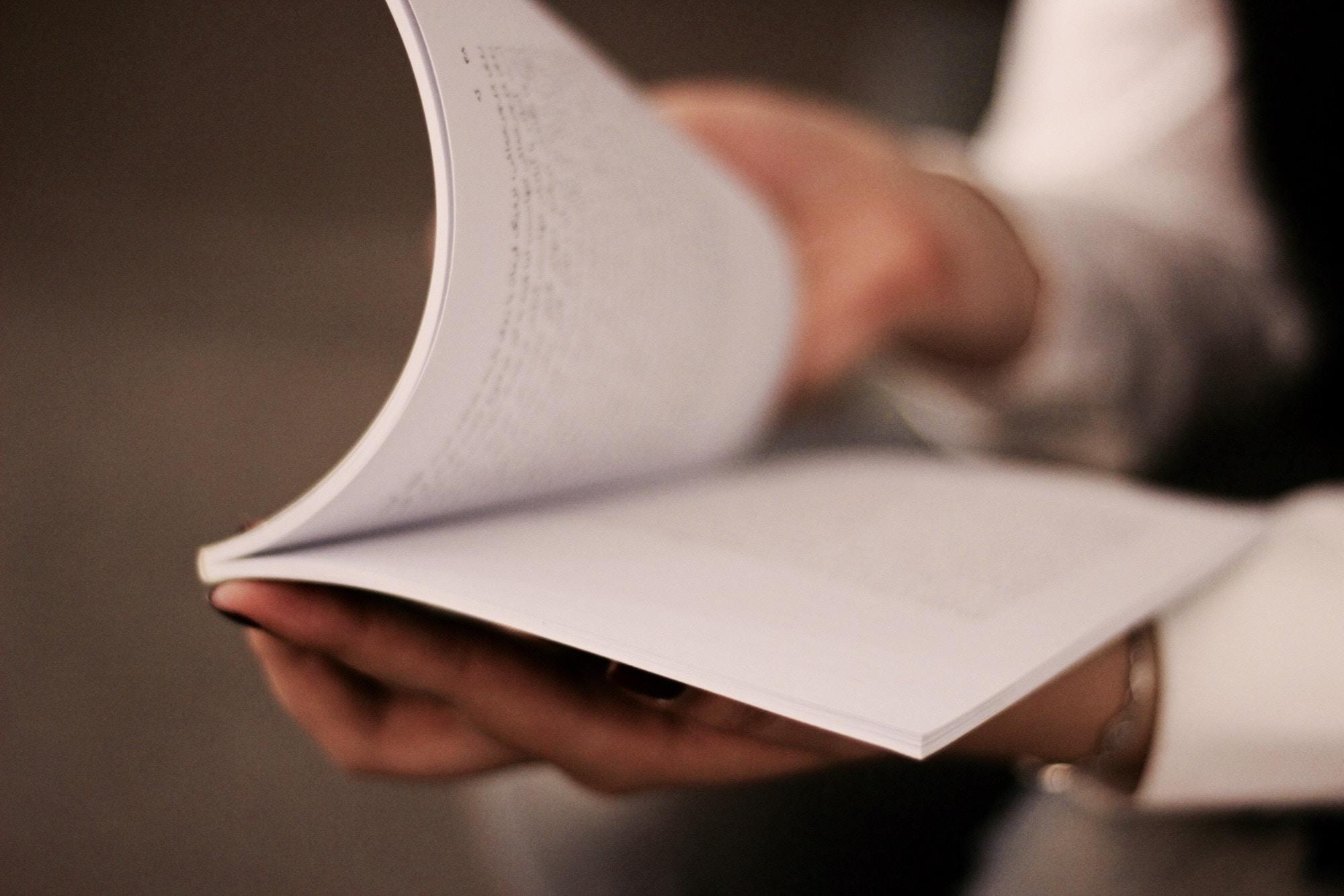 Elinde ince bir kitap tutan insan