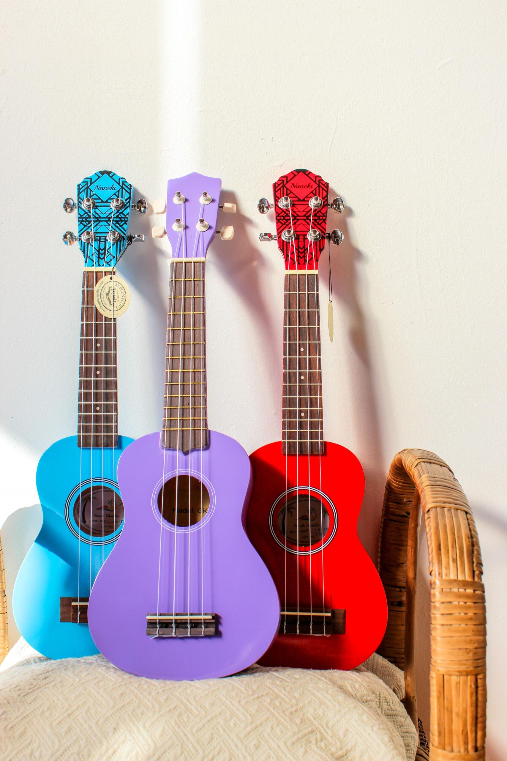 Mavi, mor ve kırmızı renklerde üç ukulele, yan yana bir koltuğa yaslanmış şekilde duruyor.
