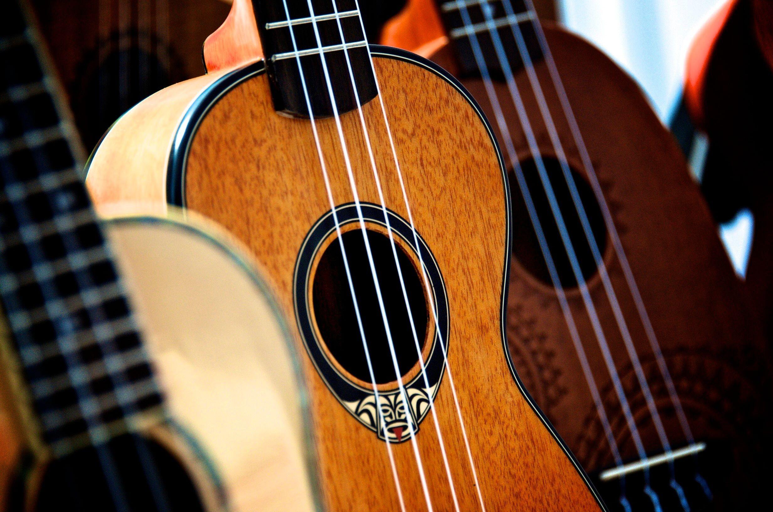 Yakın planda, farklı tonlarda ahşap gövdelere sahip birkaç ukulele yan yana görülüyor.