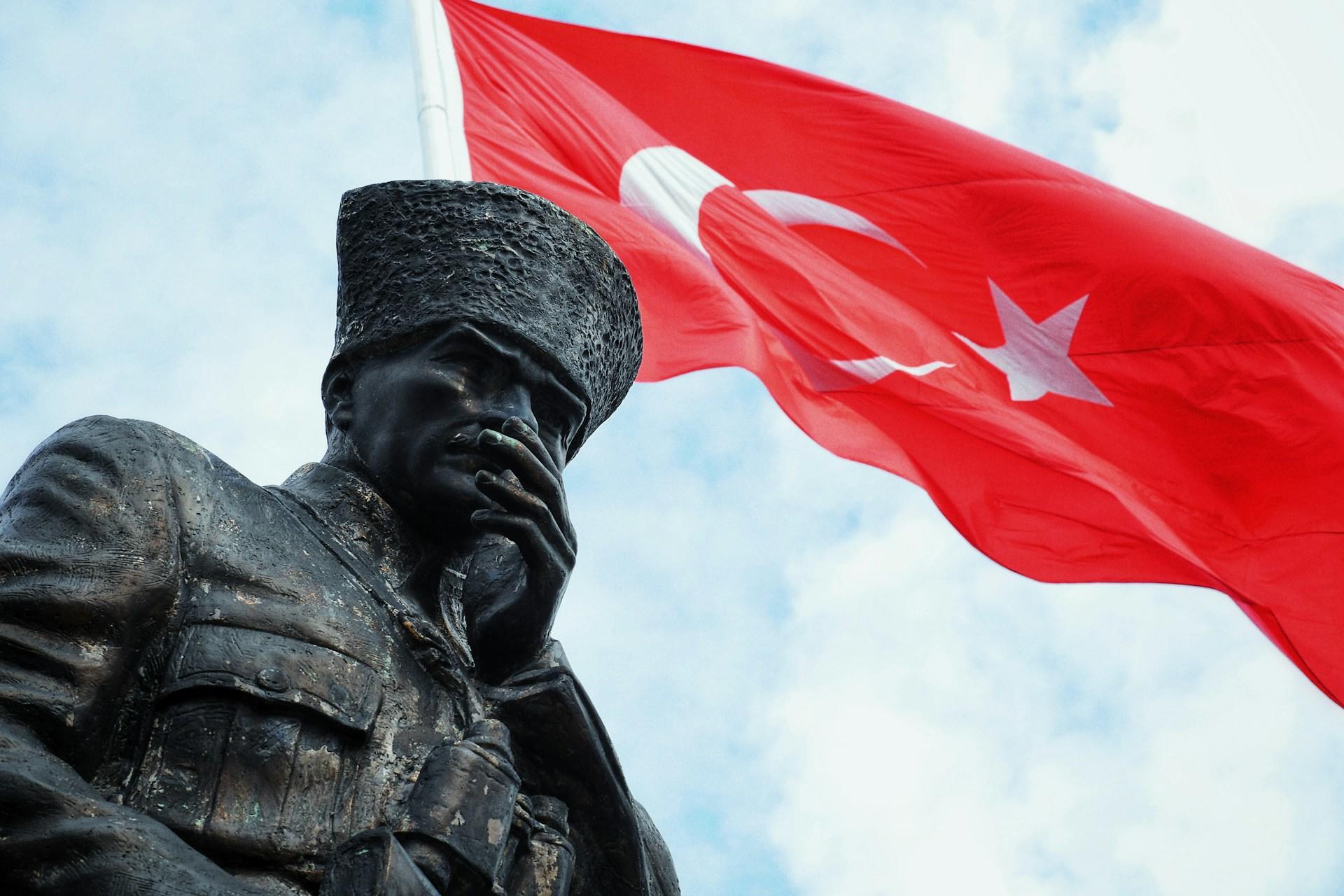 Dalgalanan Türk bayrağı önünde Atatürk heykeli.