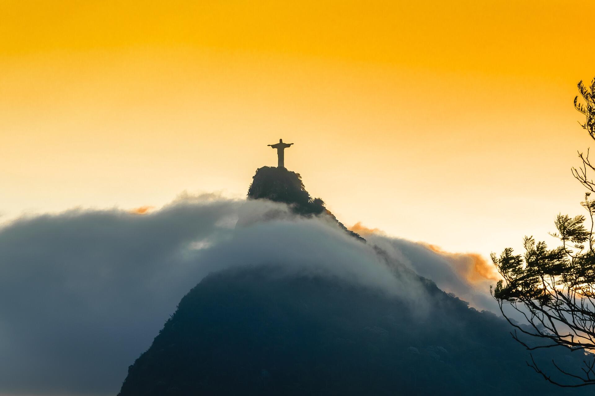 Brezilya, Rio de Janeiro’da gün batımında Corcovado Dağı’nın zirvesindeki Kurtarıcı İsa (Christ the Redeemer) heykeli, bulutların arasından siluet halinde görünüyor.