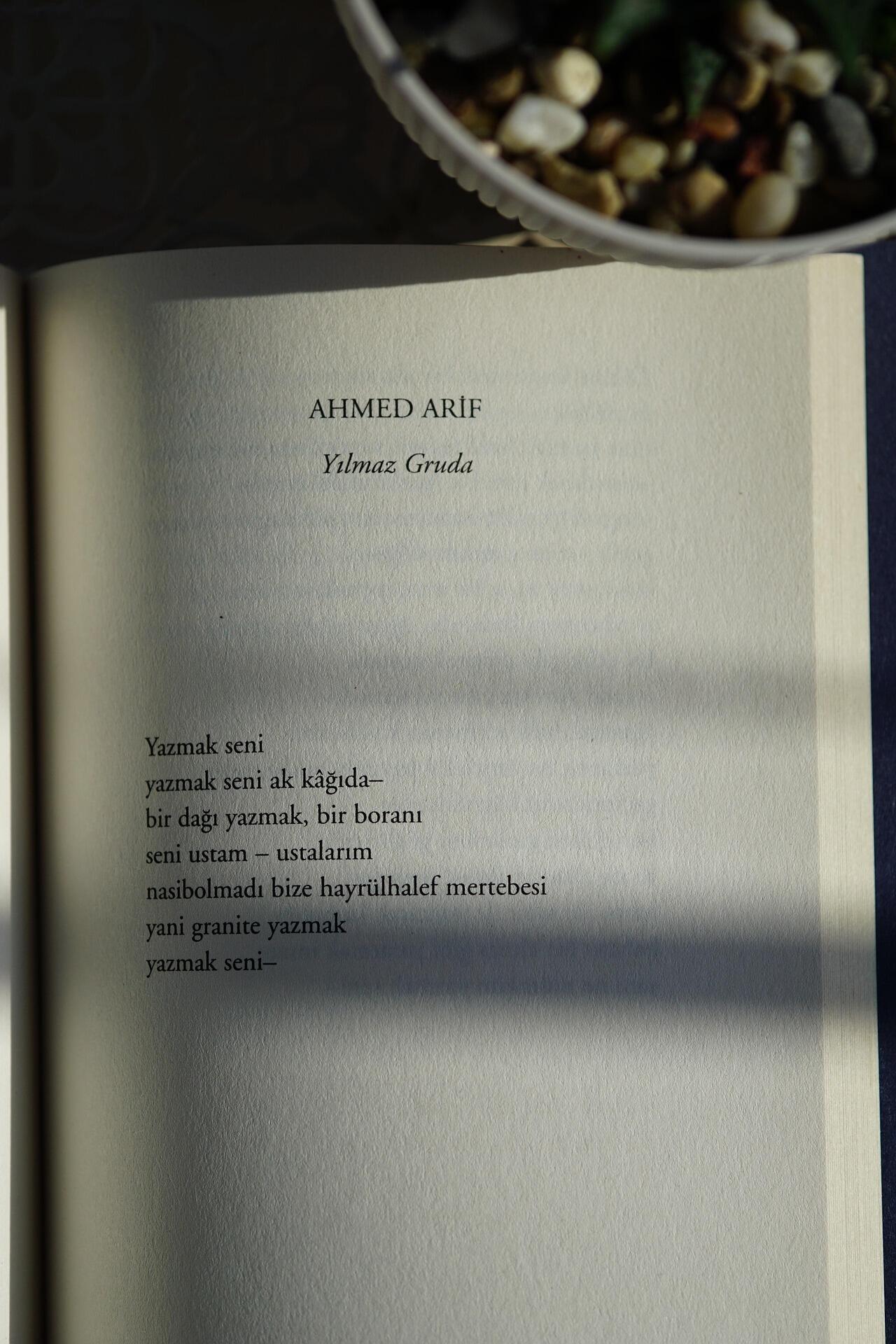 Ahmet Arif’in şiirinin yer aldığı açık kitap sayfası, gün ışığında çekilmiş şiir metni ve sayfanın üst kısmında şairin adı.