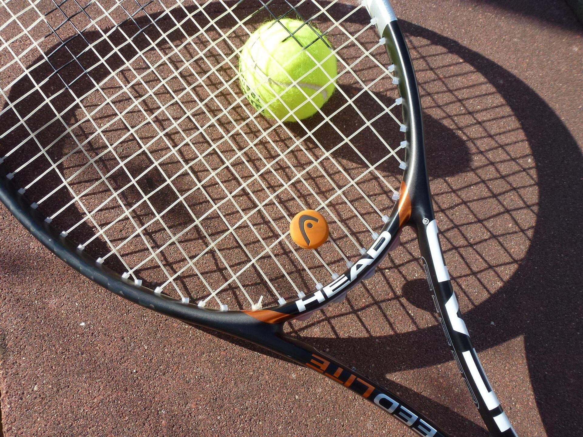 yerde duran tenis topu üzerine kapanmış bir tenis raketi