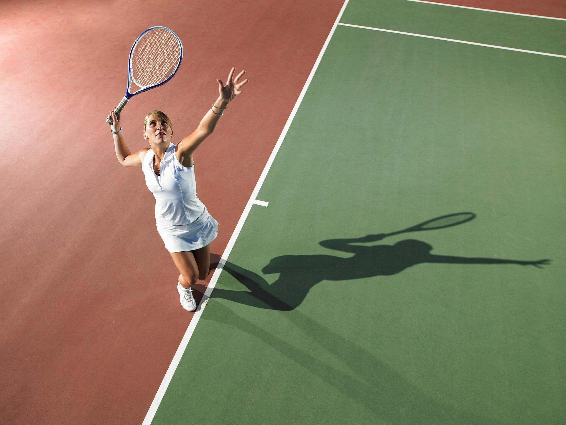 tenis topunu havaya kaldırmış vumak üzere olan bir kadın tenisçi