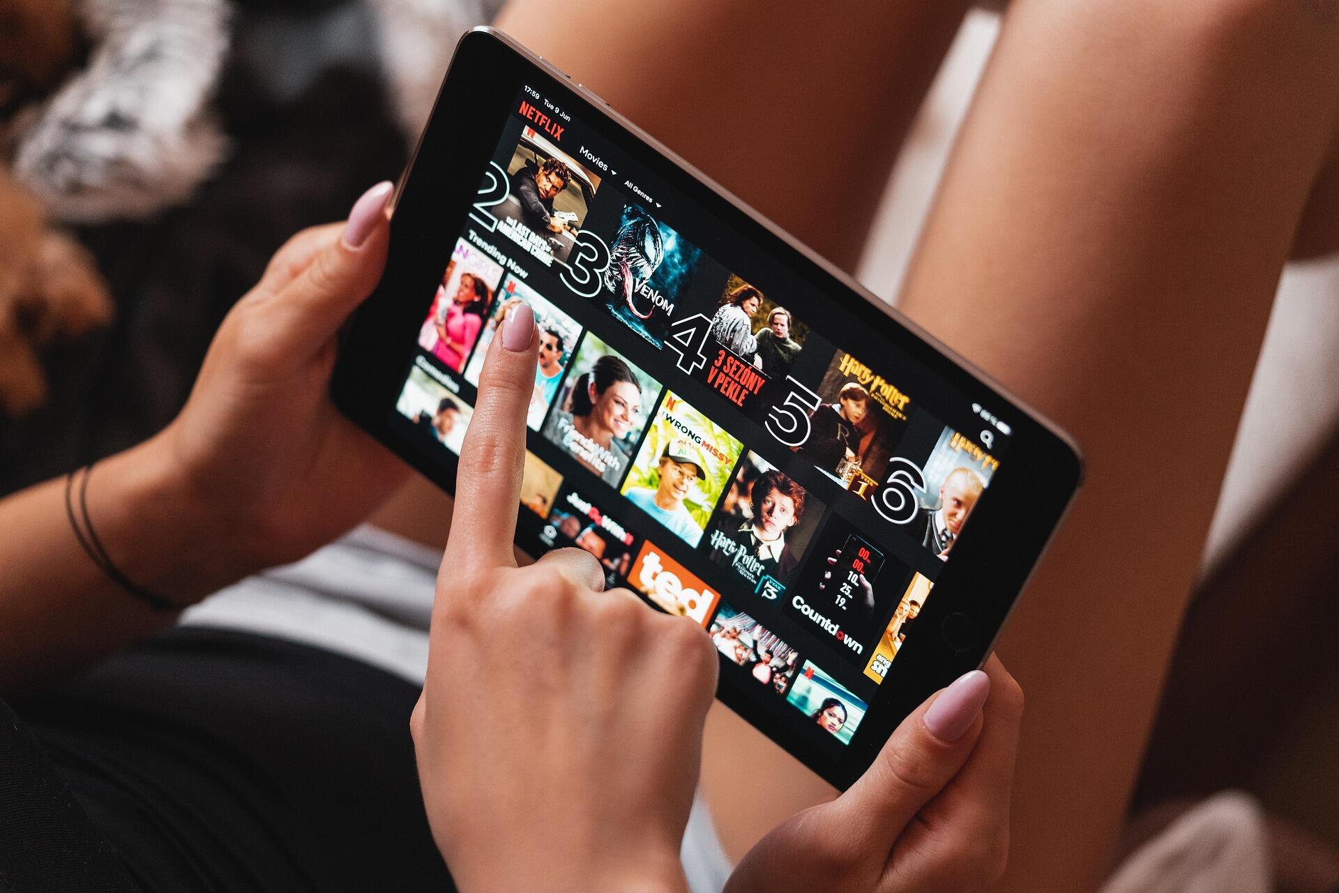 Telefonunda netflix uygulamasında gezinen bir kadın eli görseli