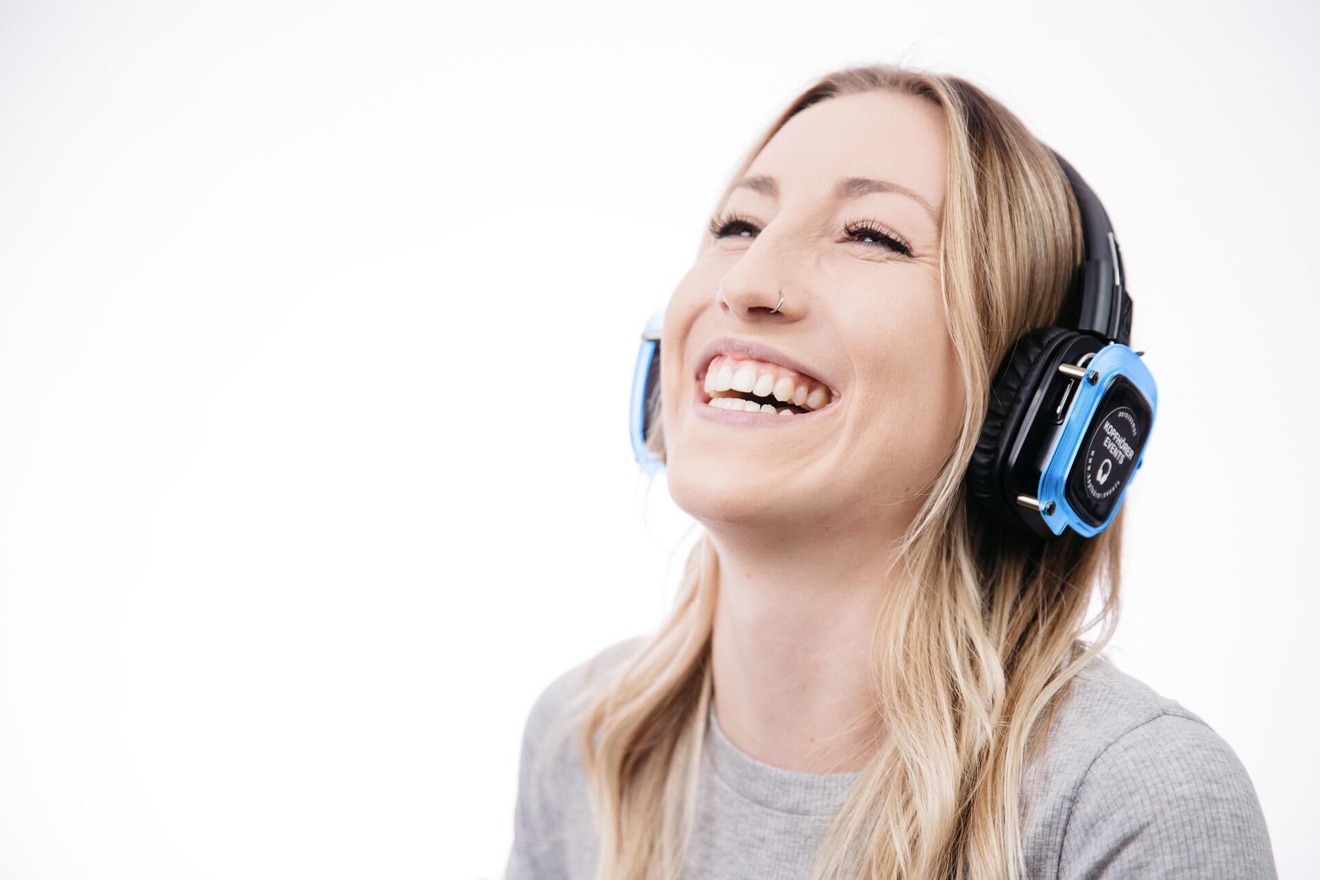 Kulağı komple saran büyük kulaklıklarla müzik dinleyen sarışın bir kadın