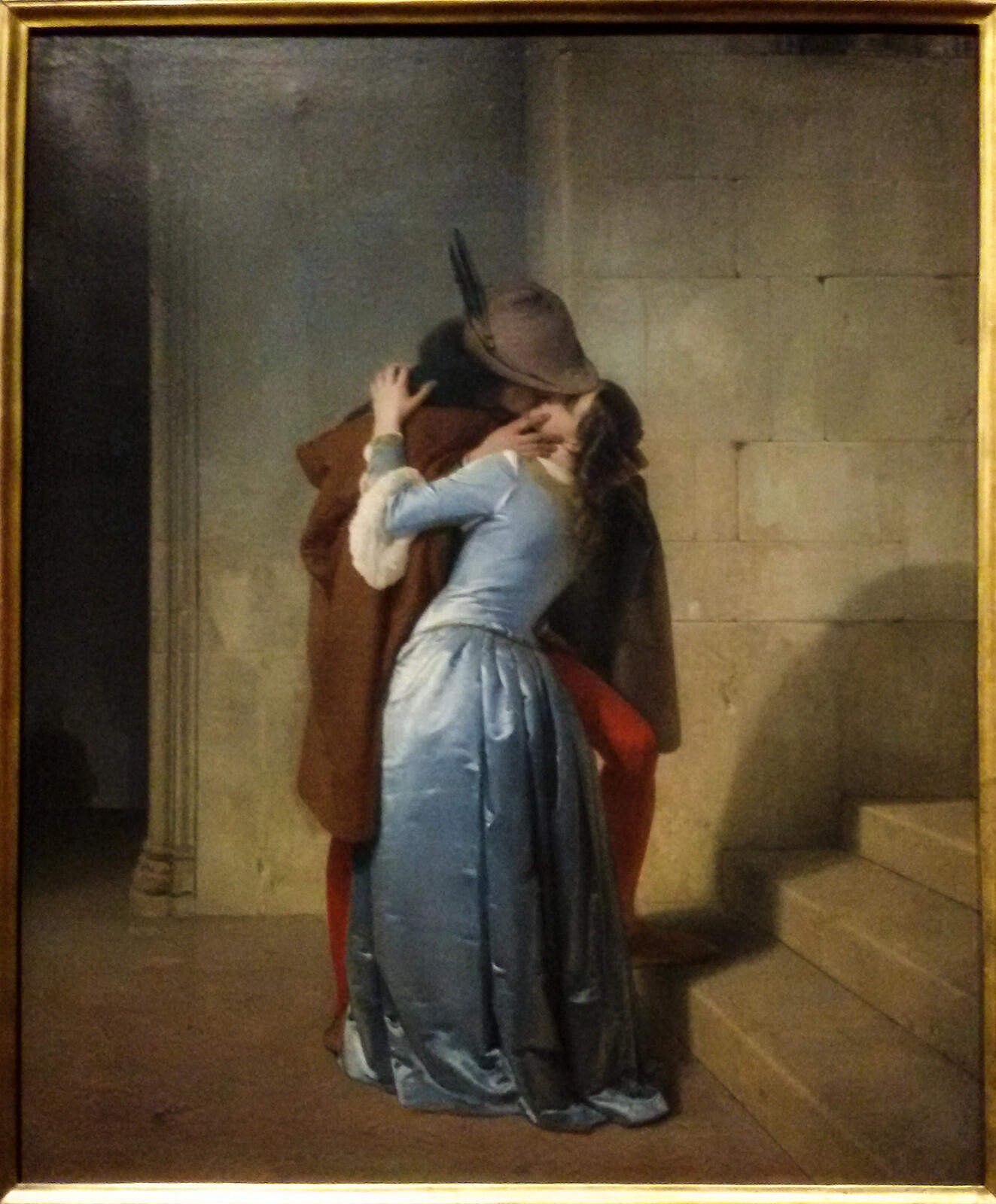 öpüşürken yüzleri gözükmeyen şapkalı bir adam ve mavi elbiseli bir kadın