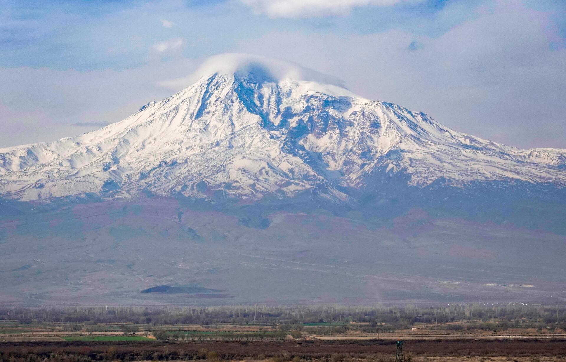 Ağrı Dağı’nın karla kaplı zirvesi, bulutların arasında yükseliyor. Türkiye’nin en yüksek dağı, Doğubayazıt ovasından bakış.