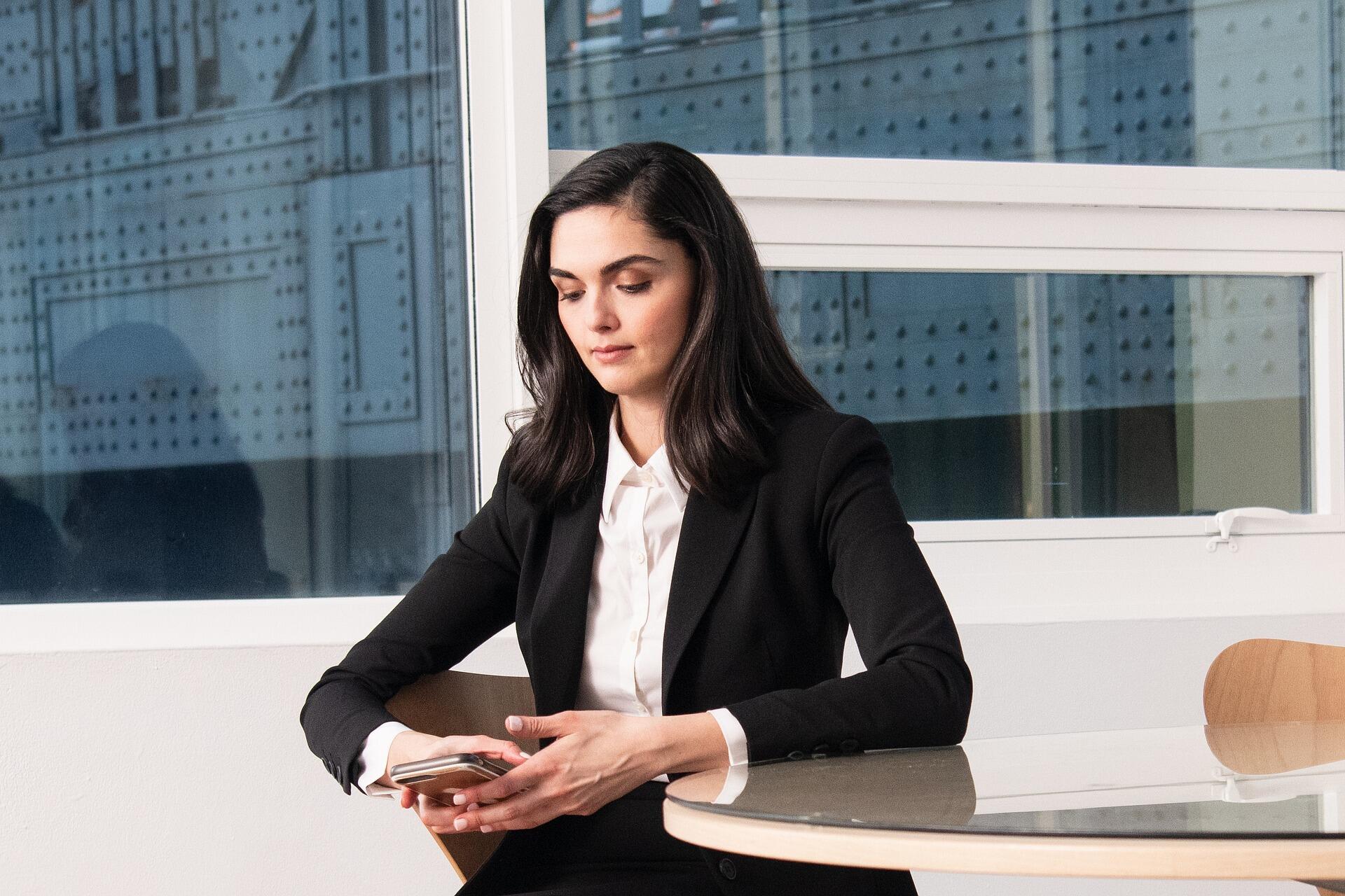 Modern bir ofis ortamında, kulaklığıyla güven veren profesyonel bir kadın Superprof müşteri temsilcisi, akıllı telefonuyla yardım taleplerini yanıtlamaya hazır.