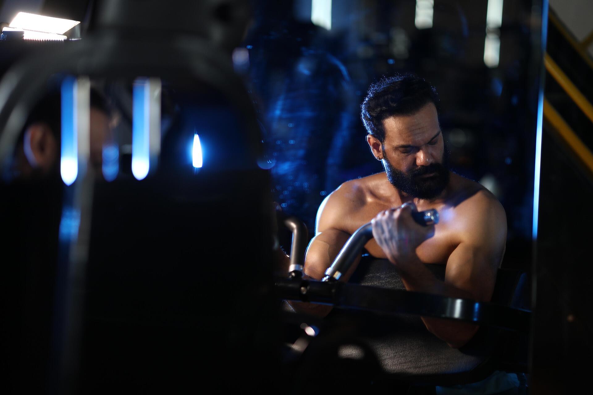 Spor salonunda biceps curl hareketi yapan genç bir erkek