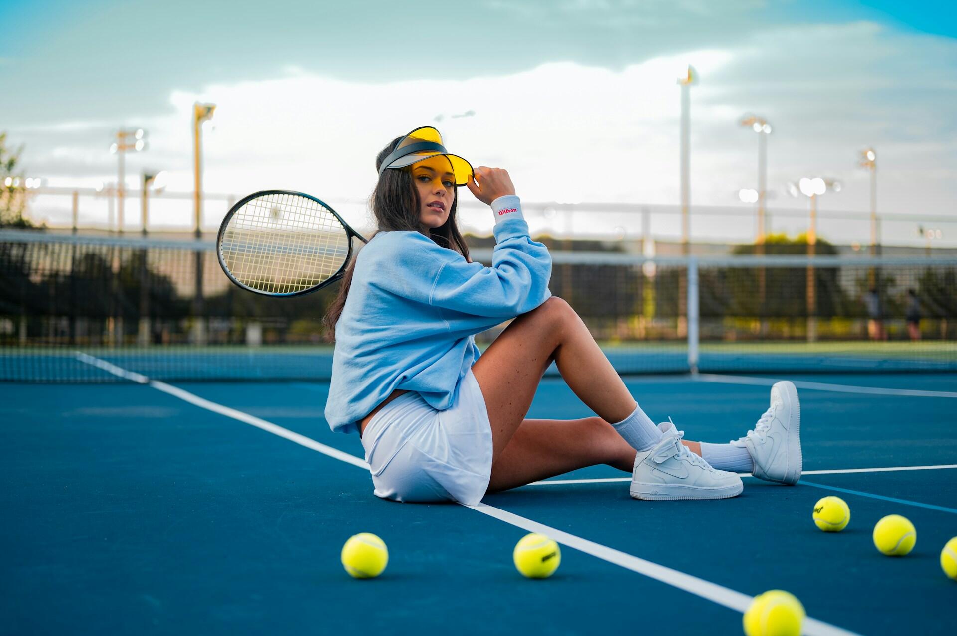 mavi bir tenis kortunda oturarak poz veren bir kadın tenisçi