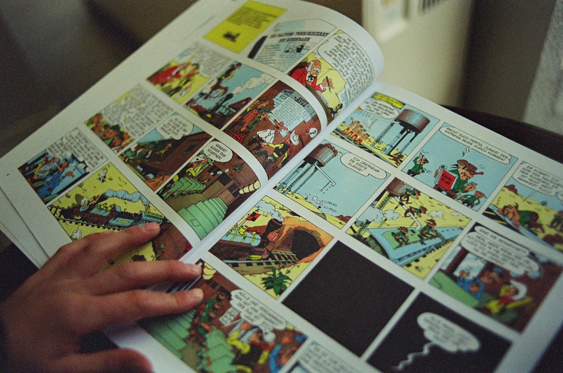 розгорнута книга коміксів з малюнками, дитяча рука на згині