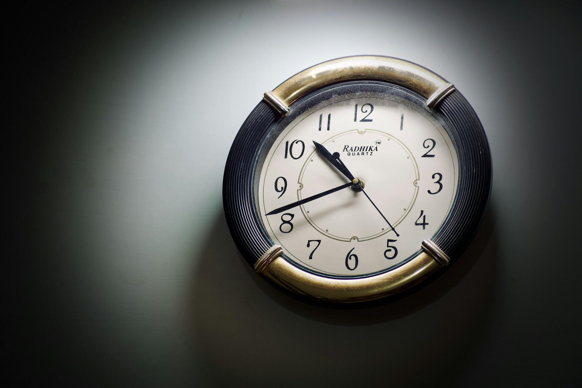 Круглий настінний годинник у плямі світла на темній стіні
