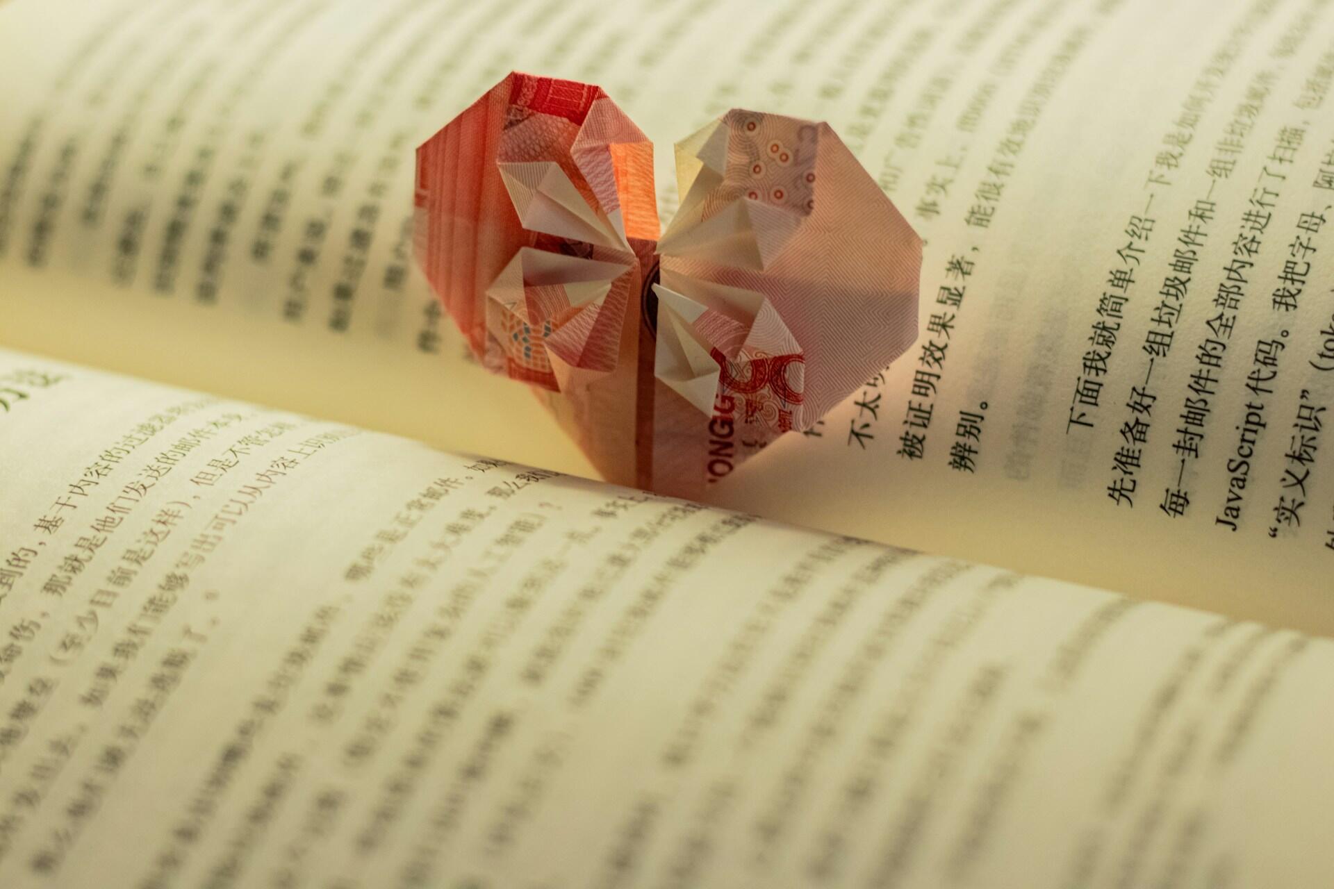 Відкрита книга з китайськими ієрогліфами із саморобною закладкою-орігамі у формі серця