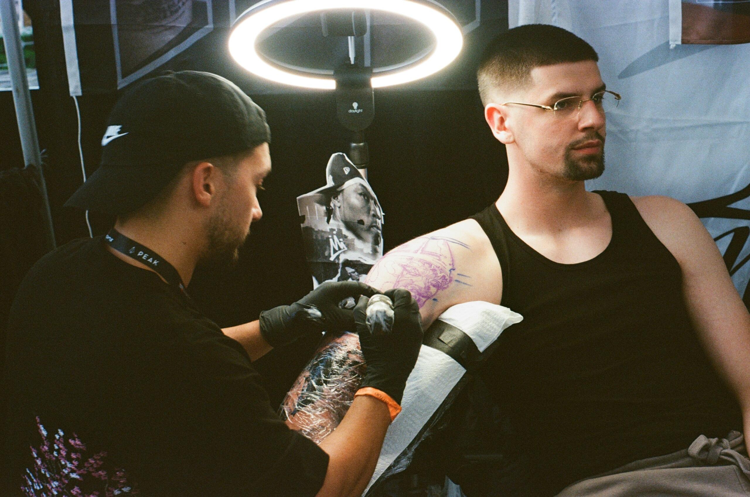 чоловіку роблять татуювання на передпліччі