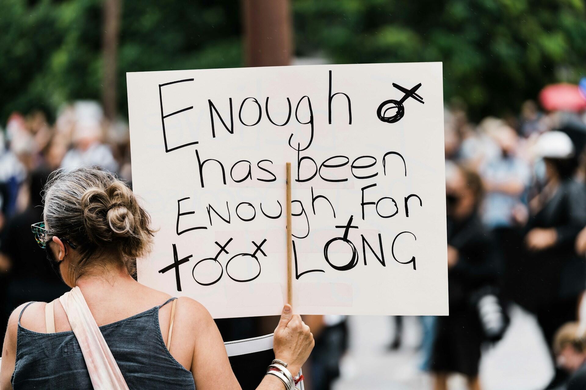 жінка під час мітингу з плакатом у руці