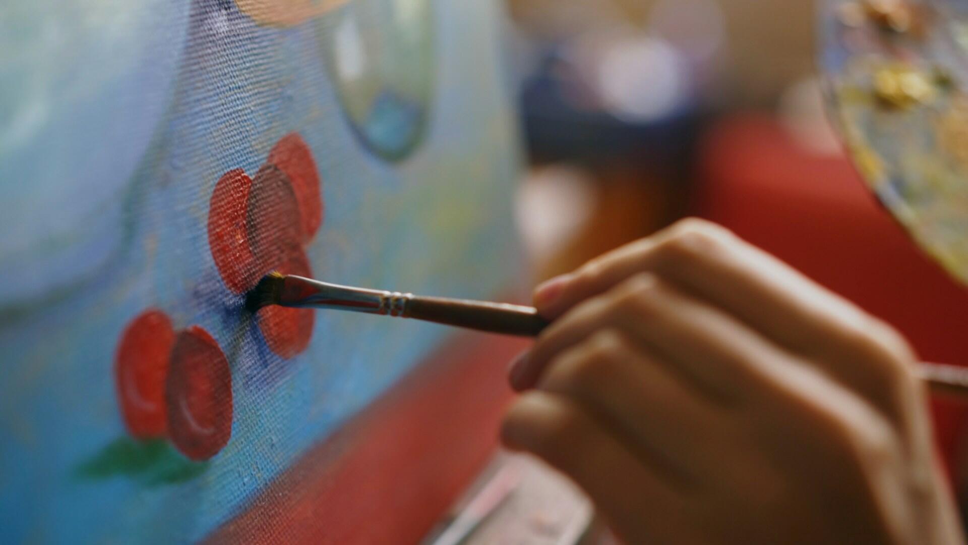 a hand is painting flowers with a brush