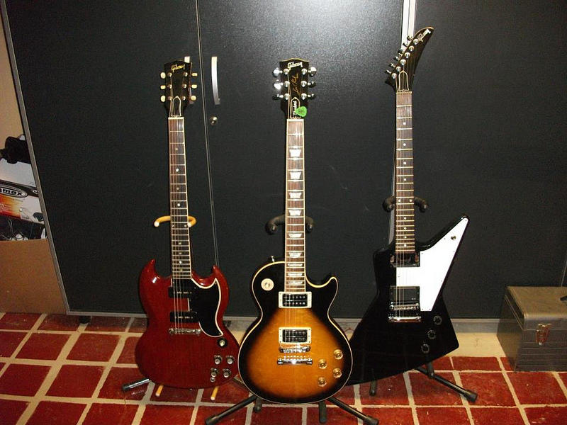 Three electric guitars stood next to each other.