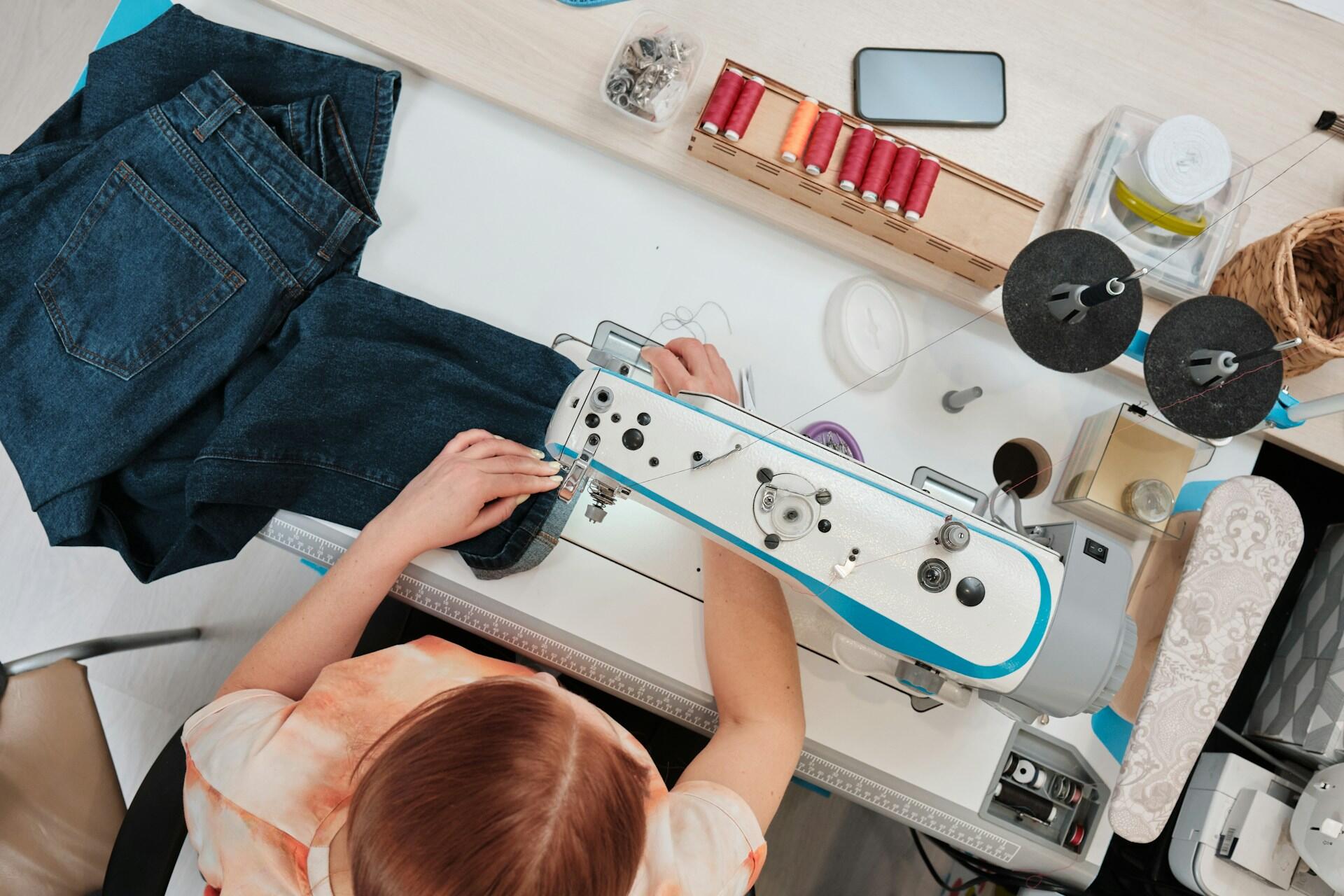 A girl sewing a pair of jean.