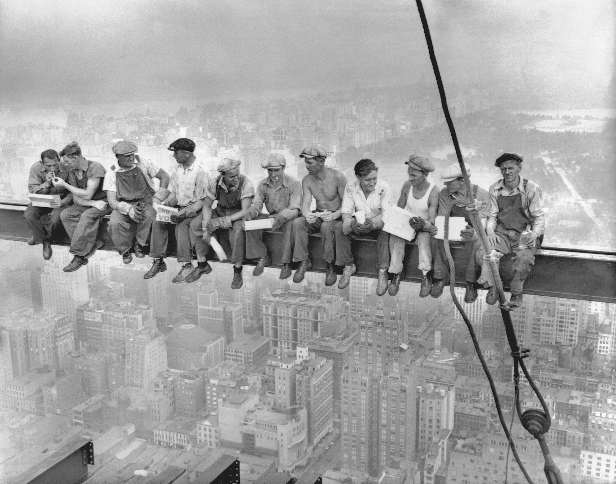 A group of construction workers sitting on a steel beam.