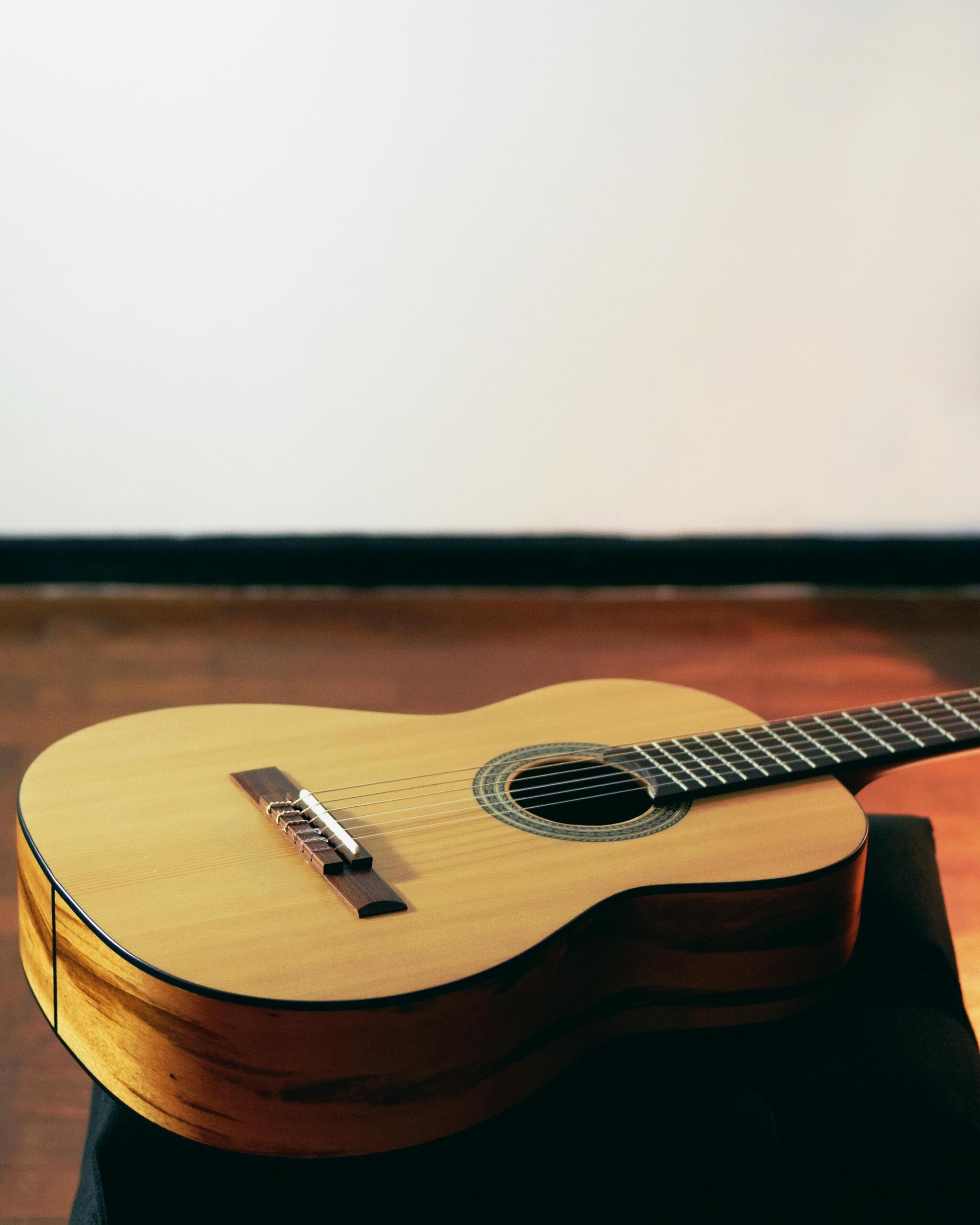 Brown acoustic guitar on the floor near a wall inside a room