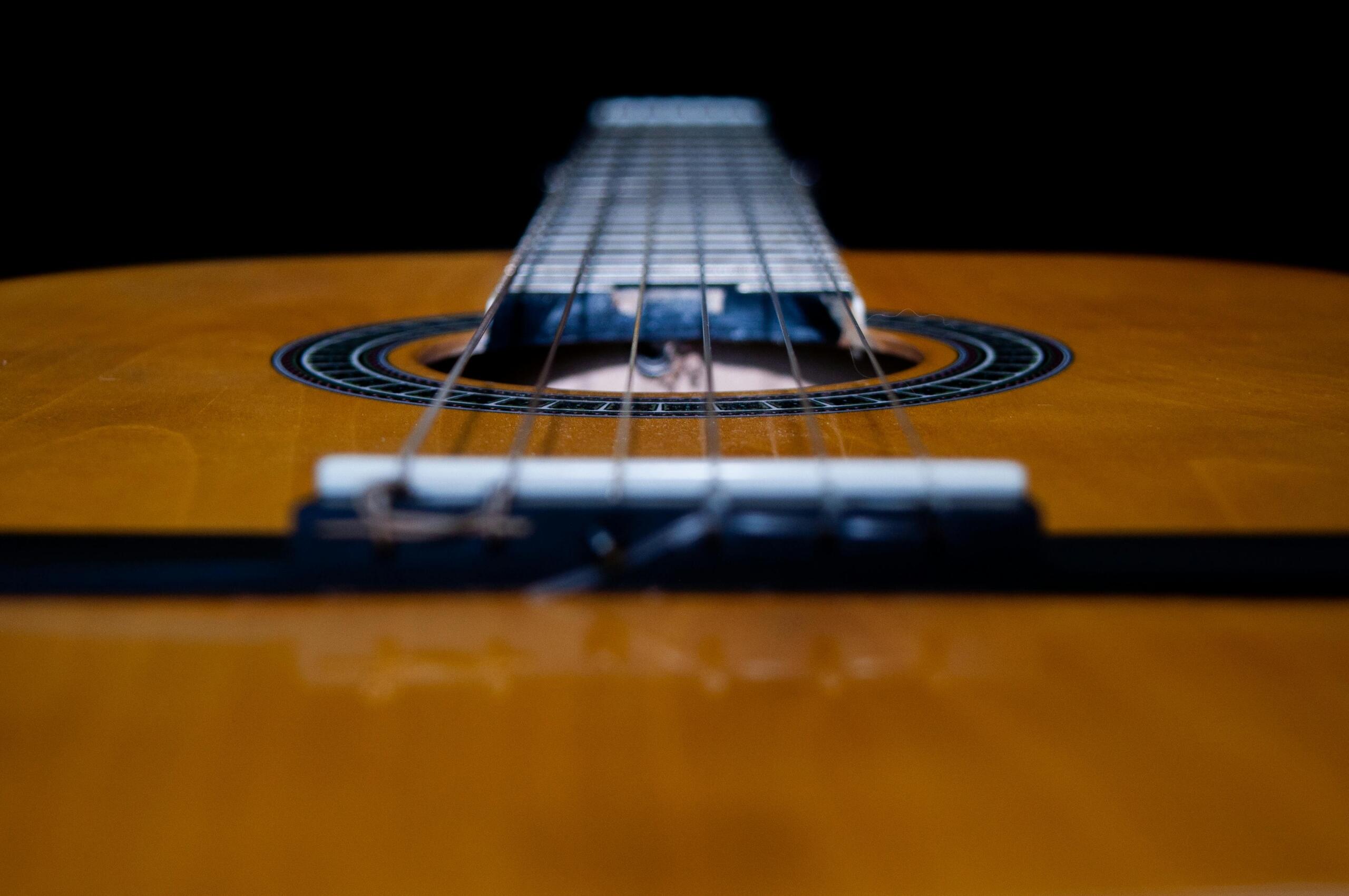 A close-up of the strings of a brown guitar