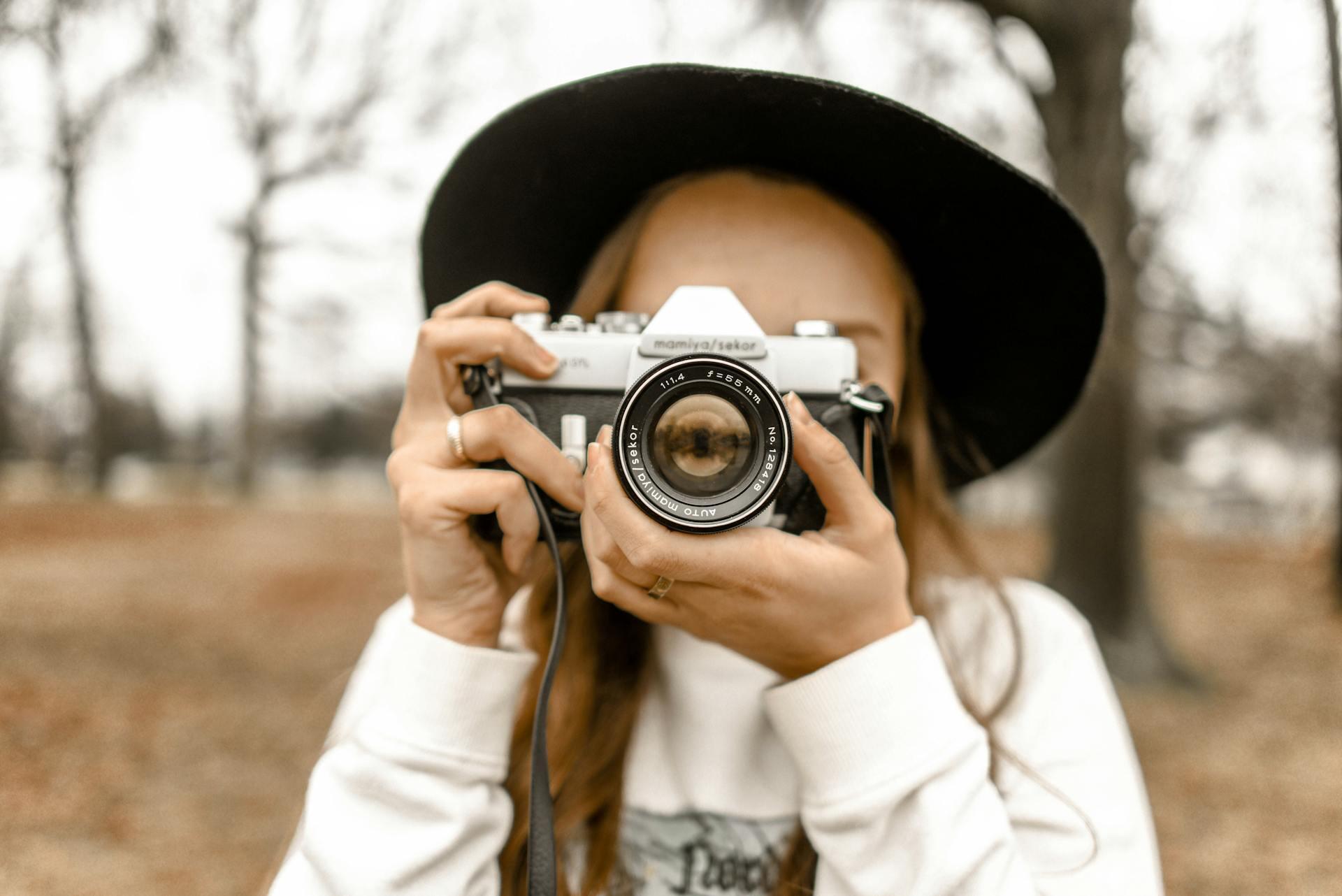 A photographer in a hat taking a picture with a camera.