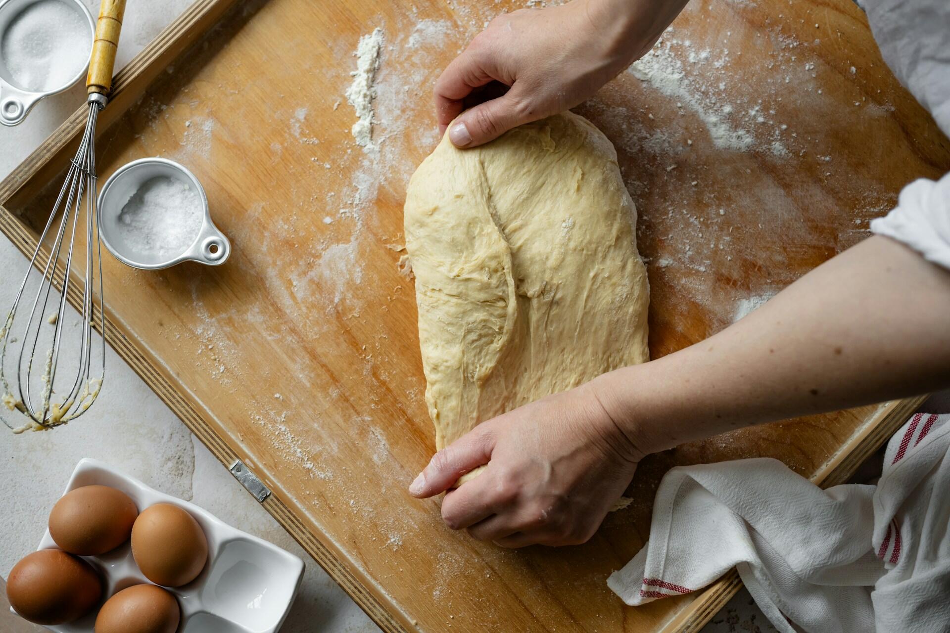 Someone rolling out dough on a cutting board.