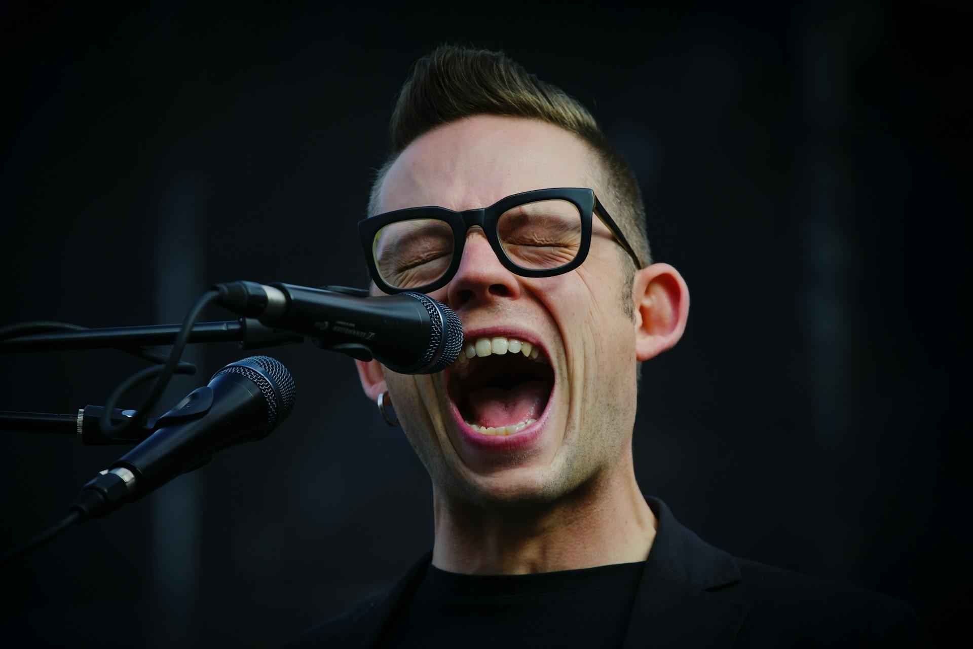A person with black glasses singing.