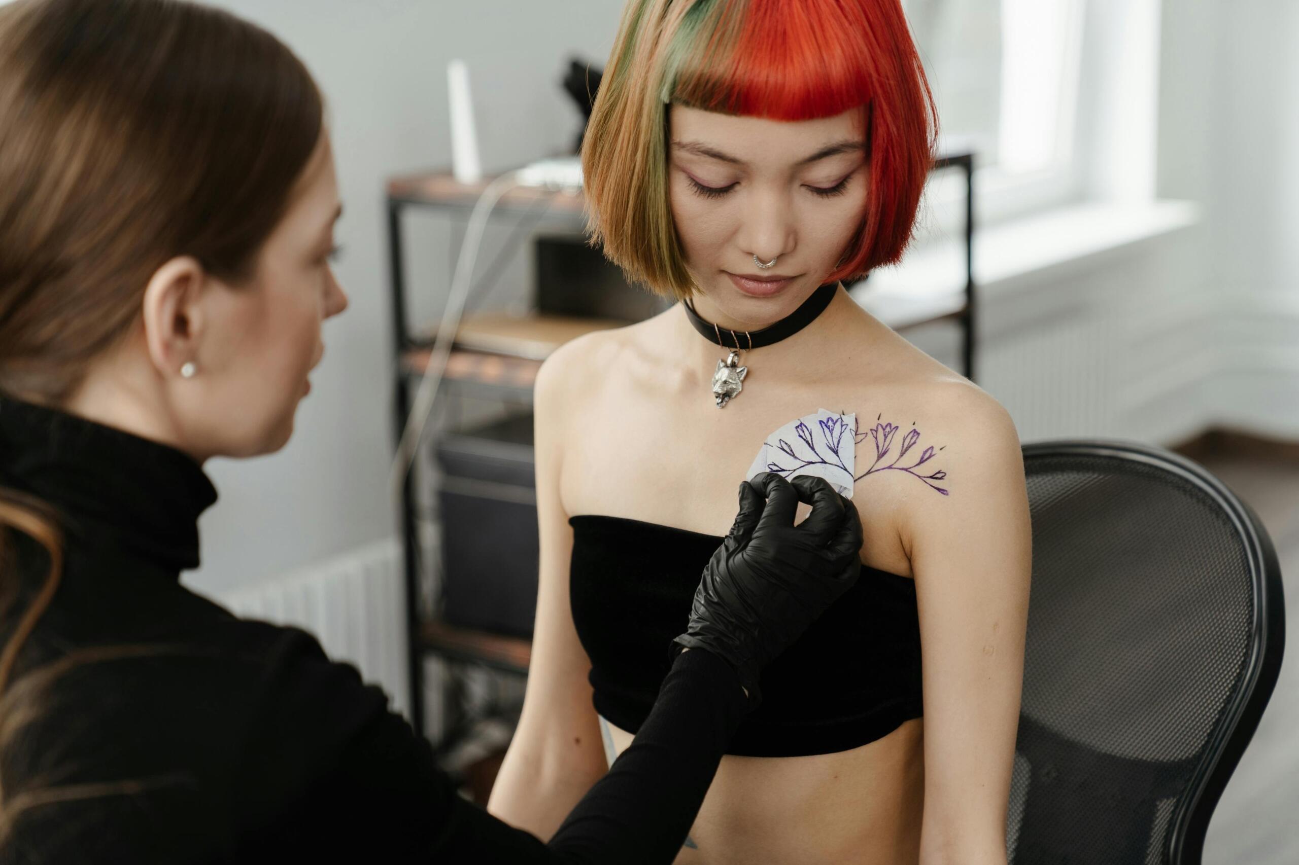 A tattoo artist is placing her design on the skin of a client