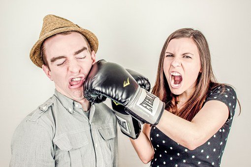 A woman wearing boxing gloves punching a man