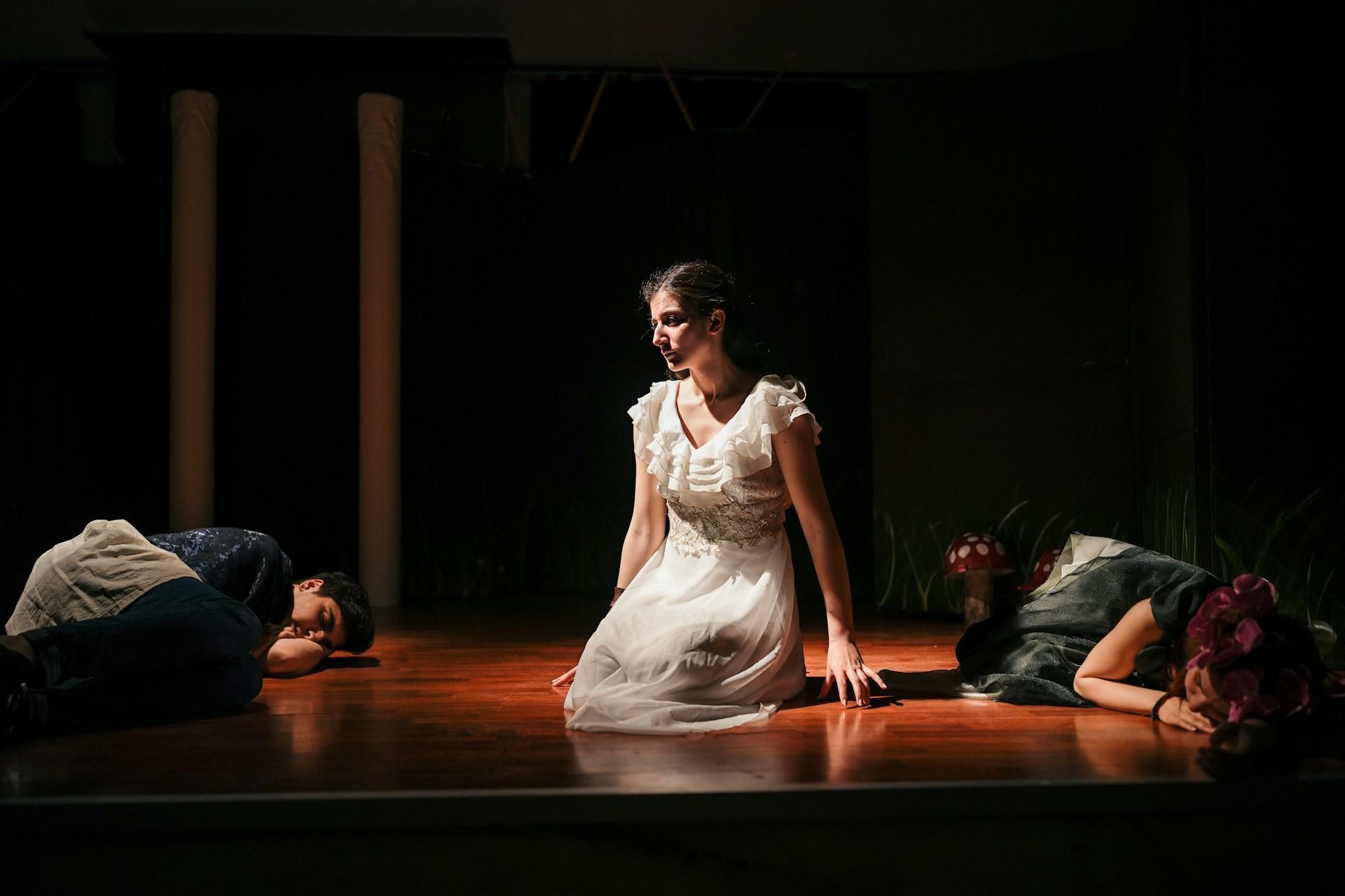 An actress on stage with two other actors performing.