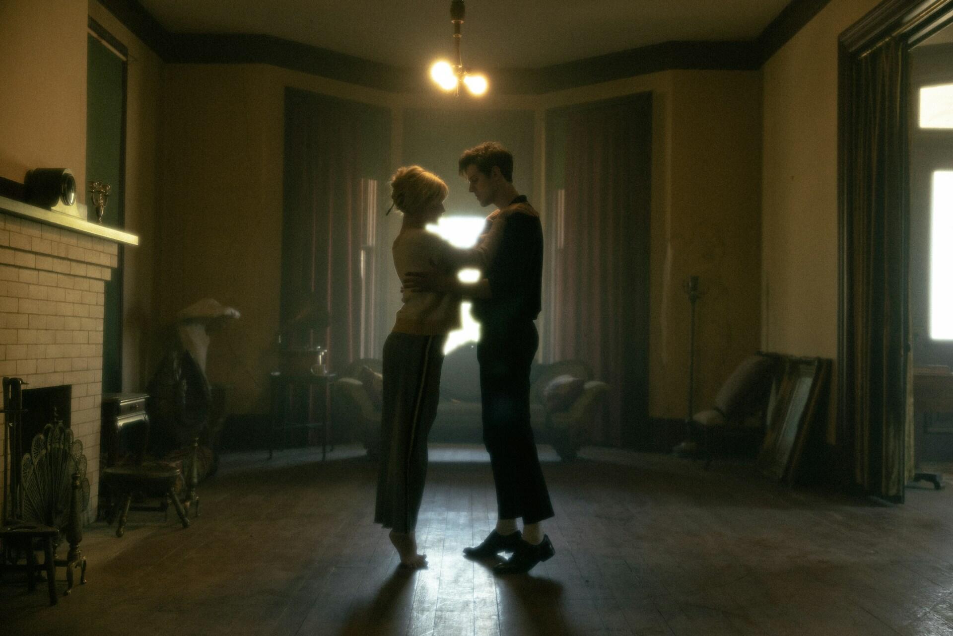 A couple dance in front of a window