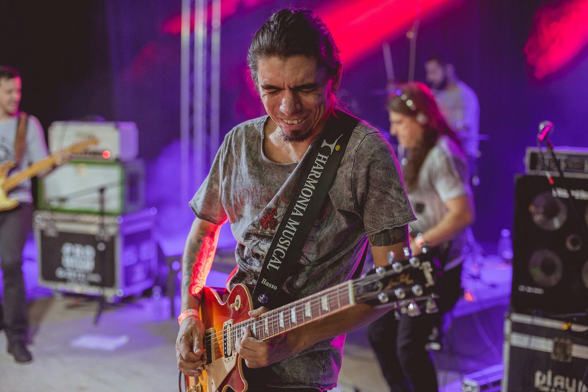 Guitarist with band in the background on stage