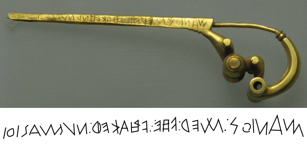 A photo of the  Praeneste fibula, a gold brooch with ancient Latin writing carved into it.