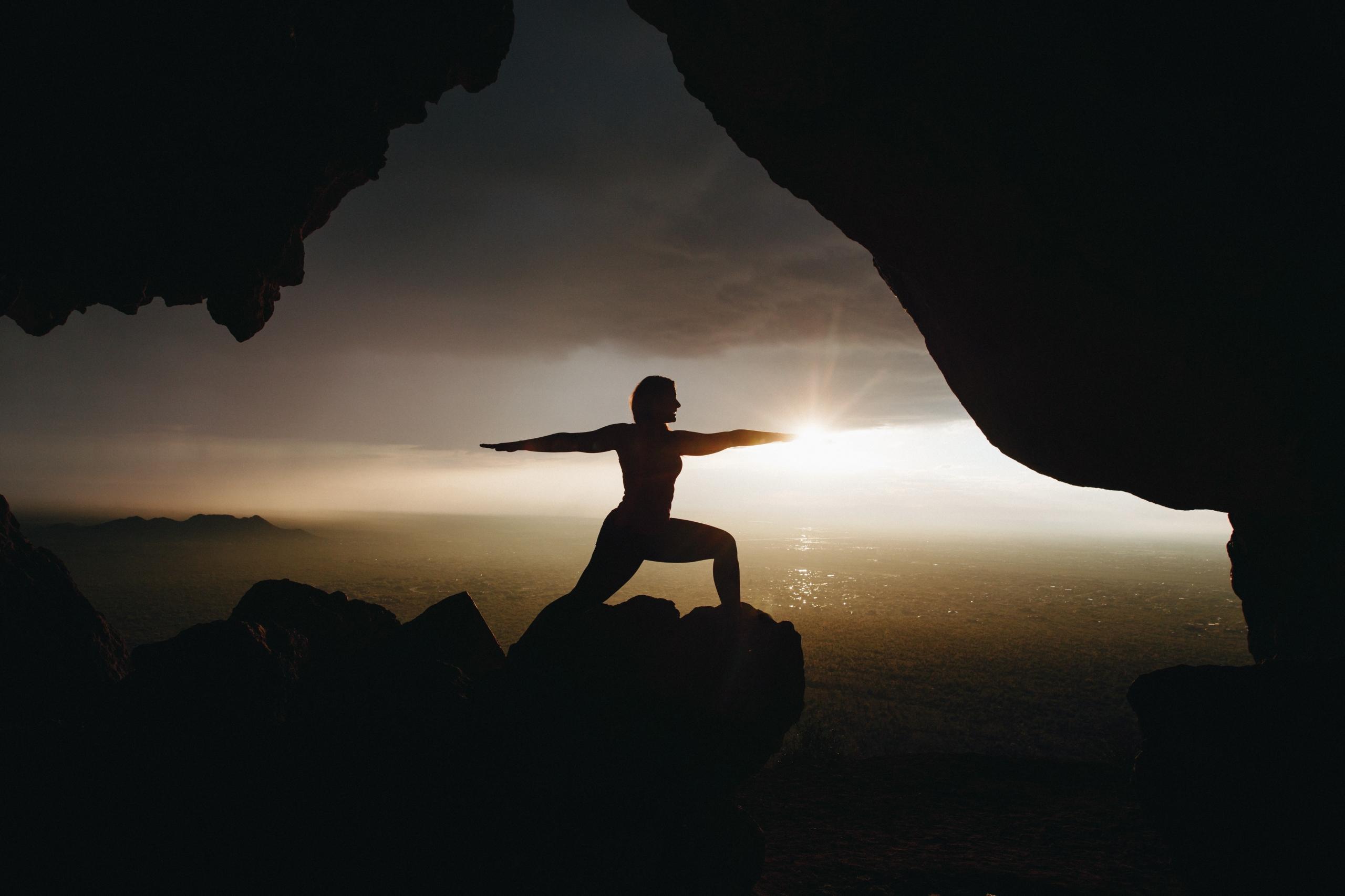 An individual practicing yoga at the edge of a cliff