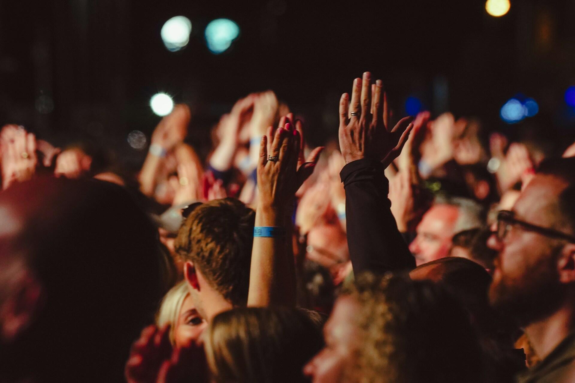 A crowd at a show, clapping hands and cheering on.